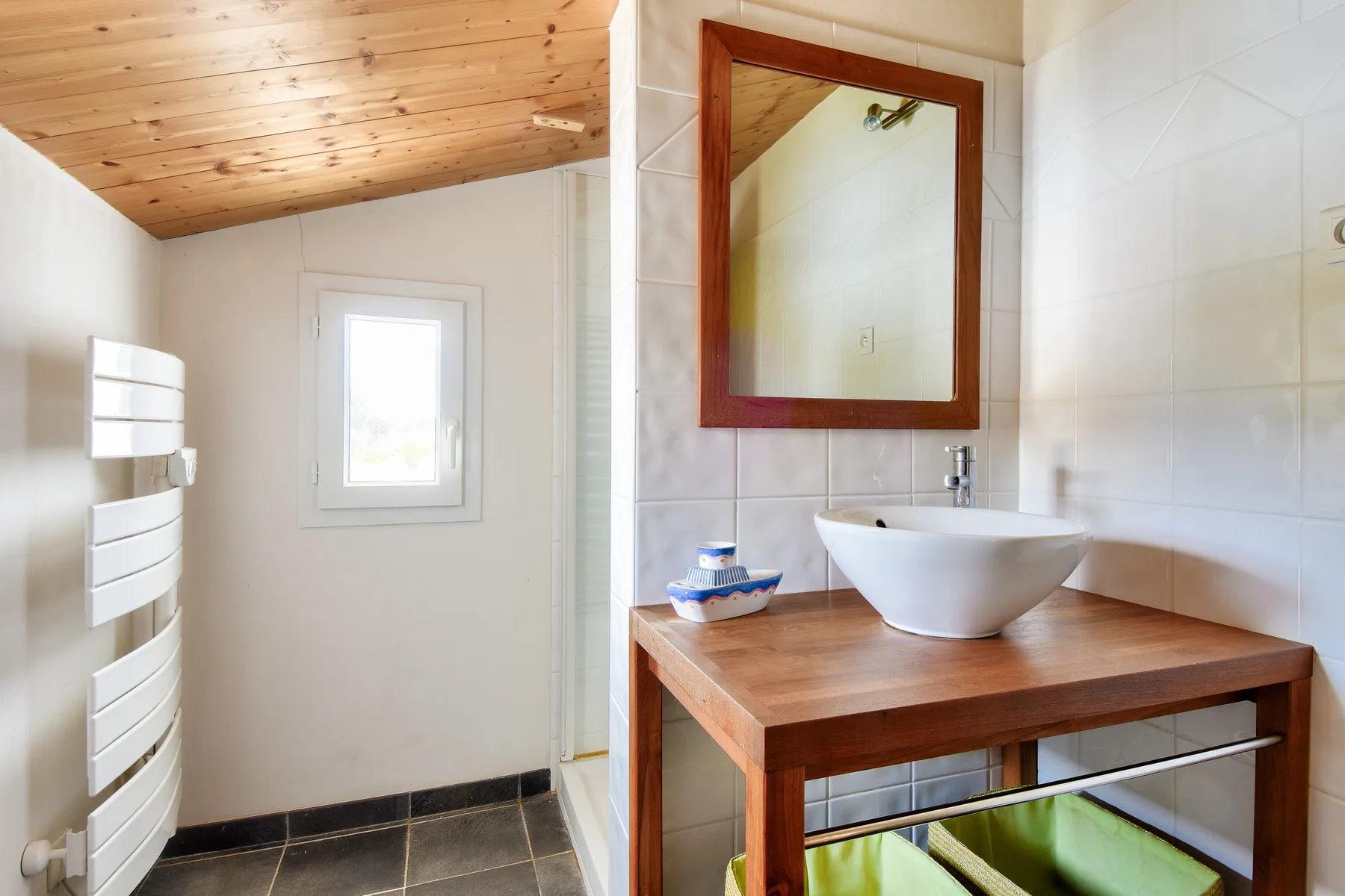 A bright bathroom with a vessel sink on a wooden vanity.
