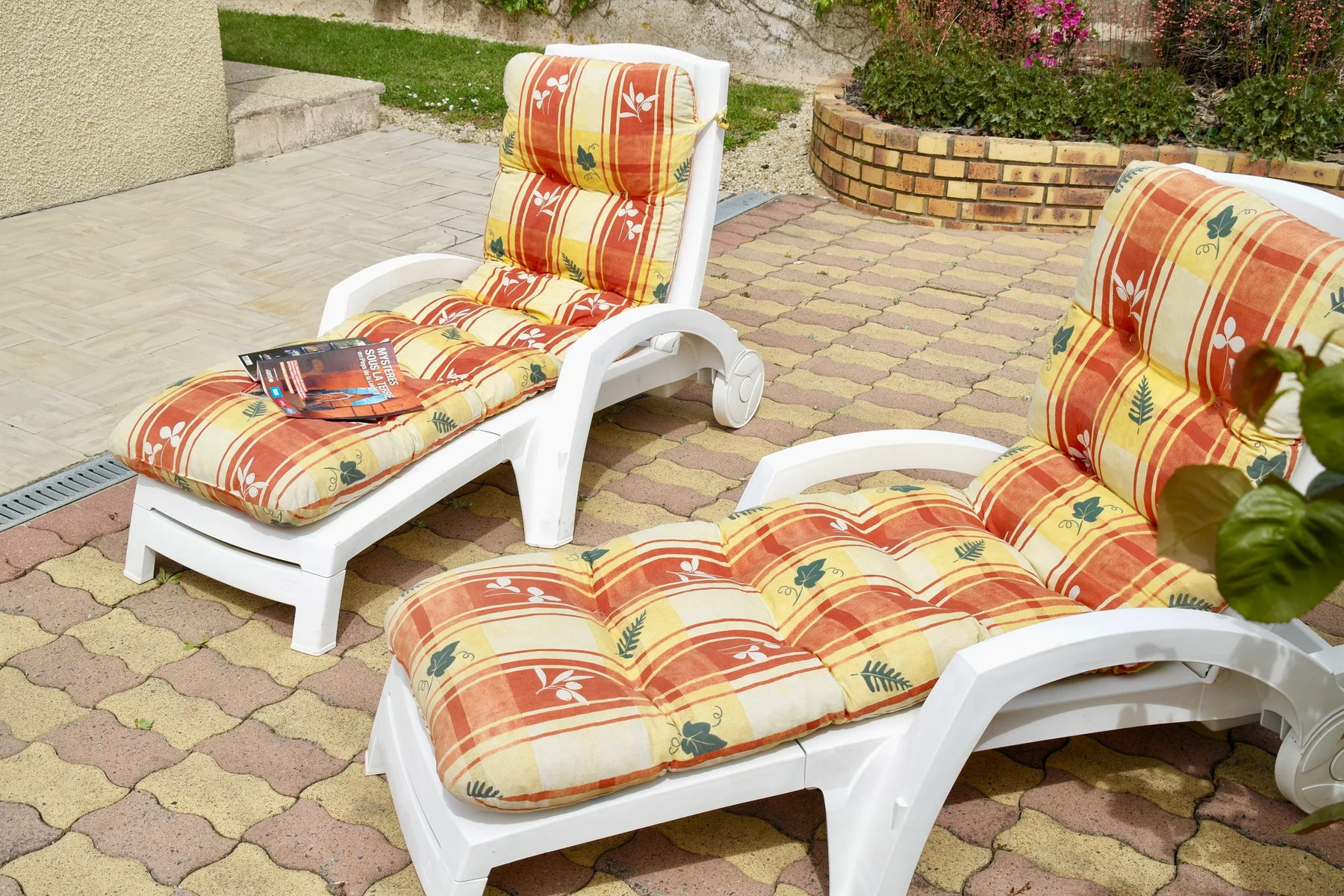 Outdoor seating with colorful cushions rests on a paved patio.
