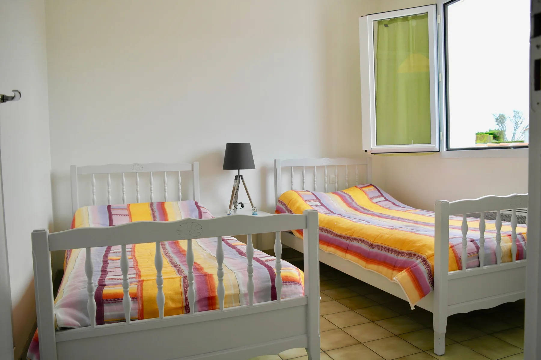 A bedroom with two beds covered in colorful striped bedding.