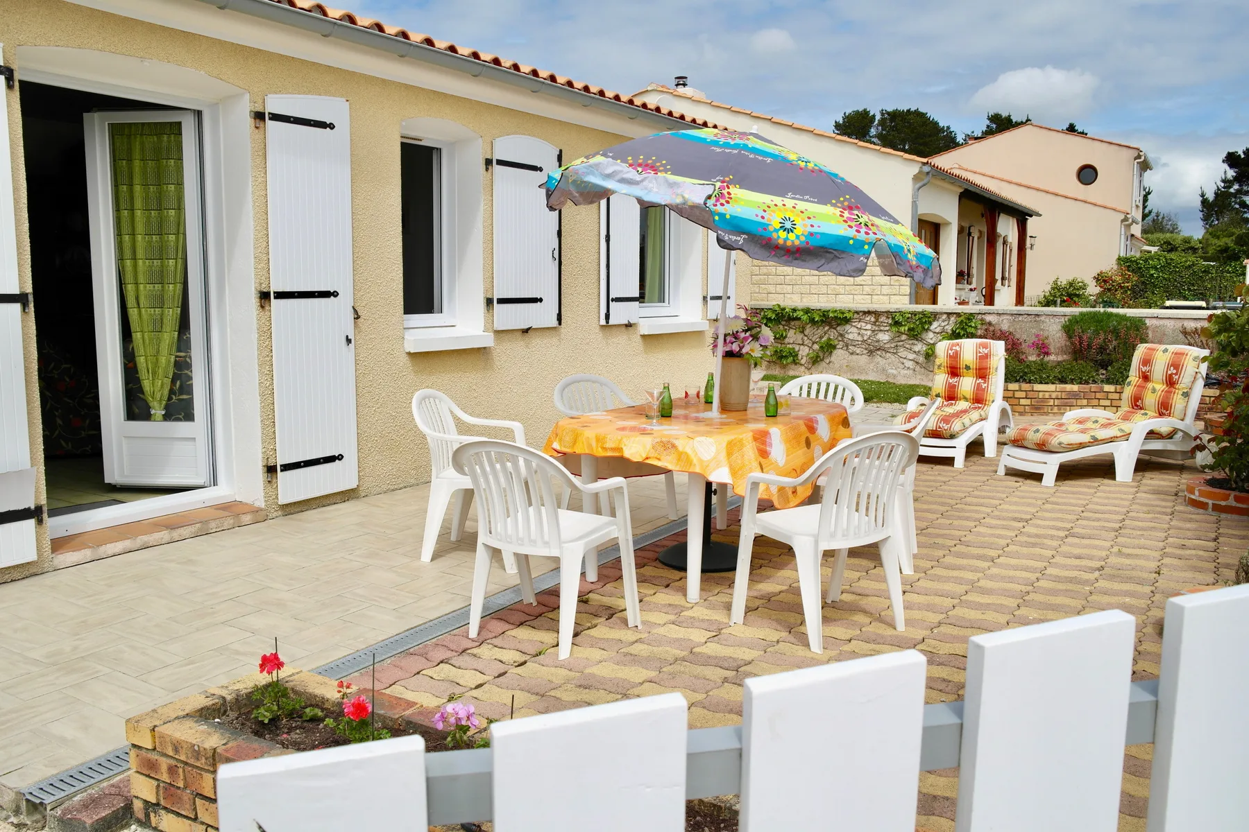 Outdoor patio with a dining table beneath a colorful umbrella.