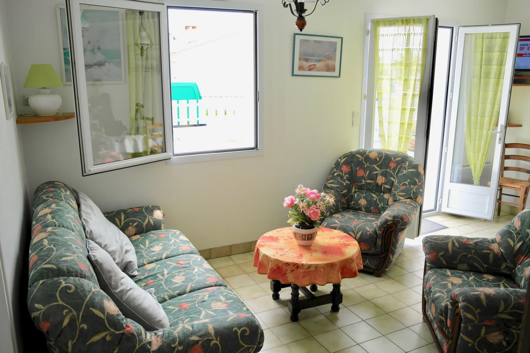 A sitting room with patterned seating around a small table of flowers.
