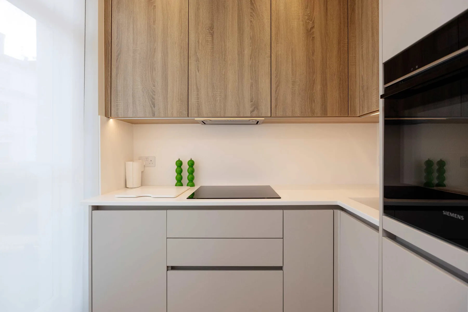 Una cocina moderna con gabinetes de madera y una placa de cocción oscura.