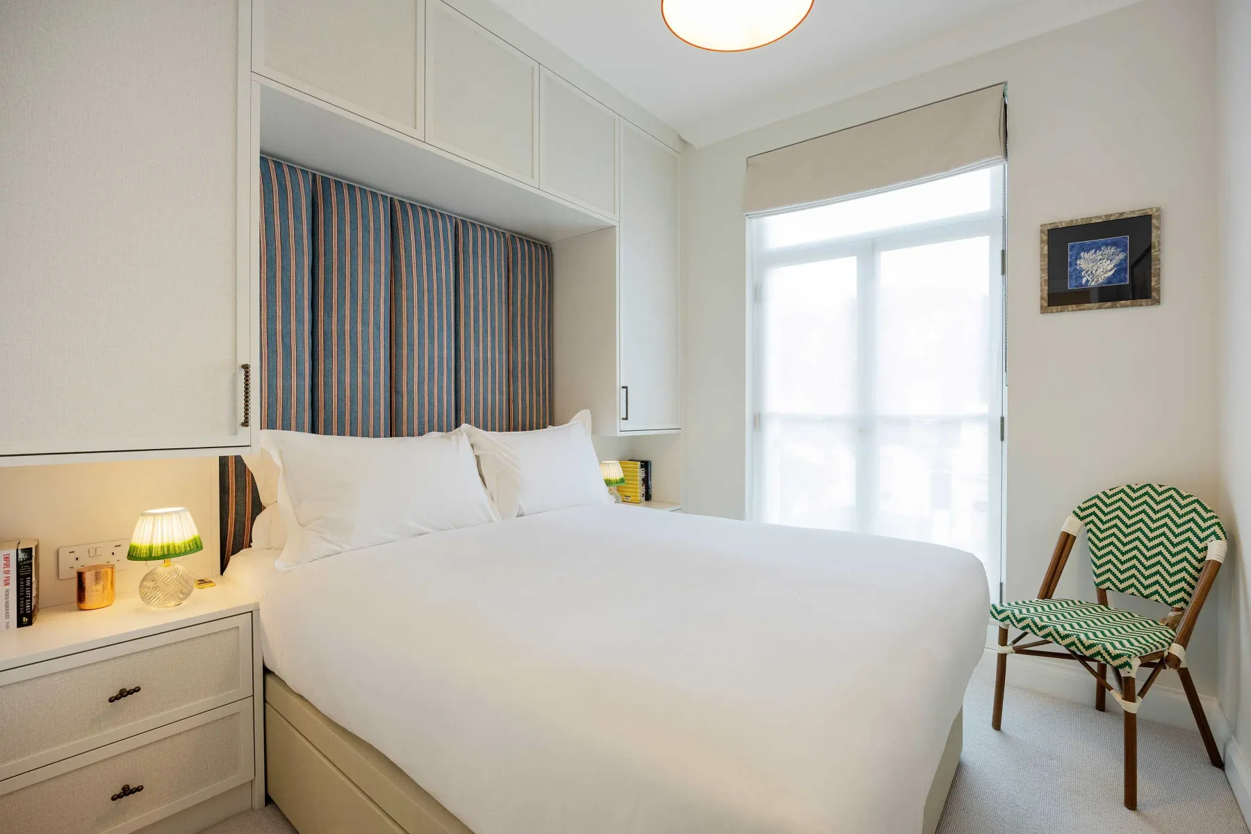 Un dormitorio con una cama bien hecha, armarios empotrados y una ventana.