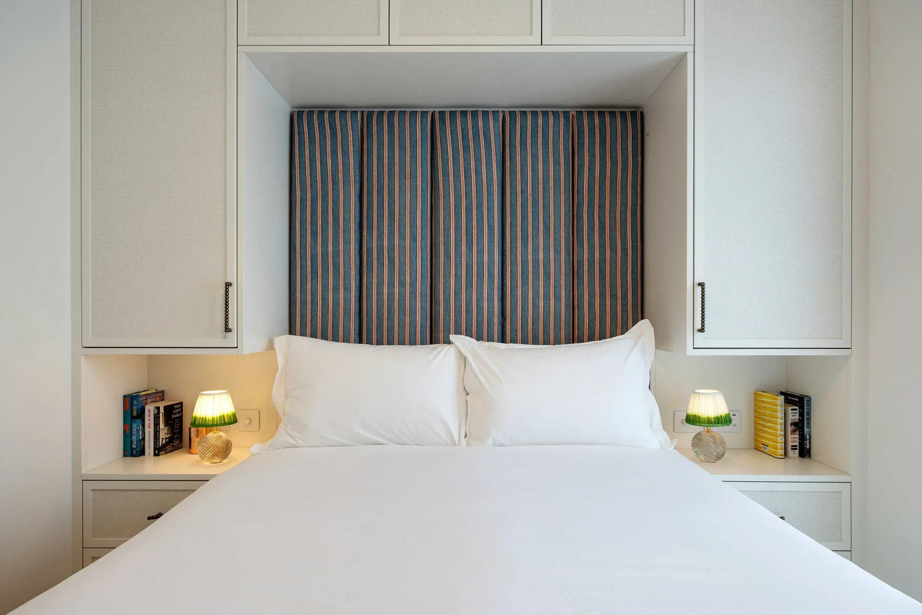 Un dormitorio con una cama bien tendida y cortinas a rayas.