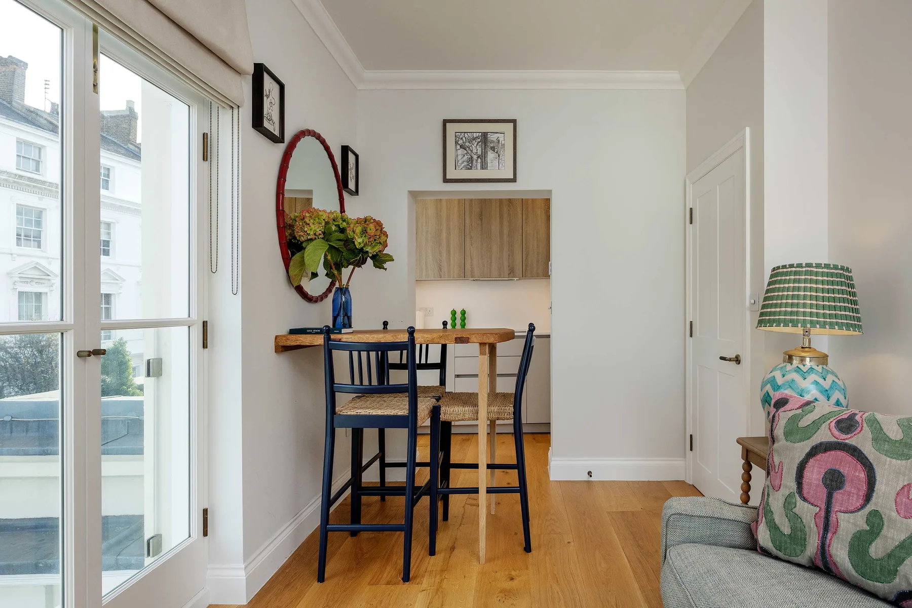 Un comedor luminoso con una mesa de madera junto a ventanas altas.