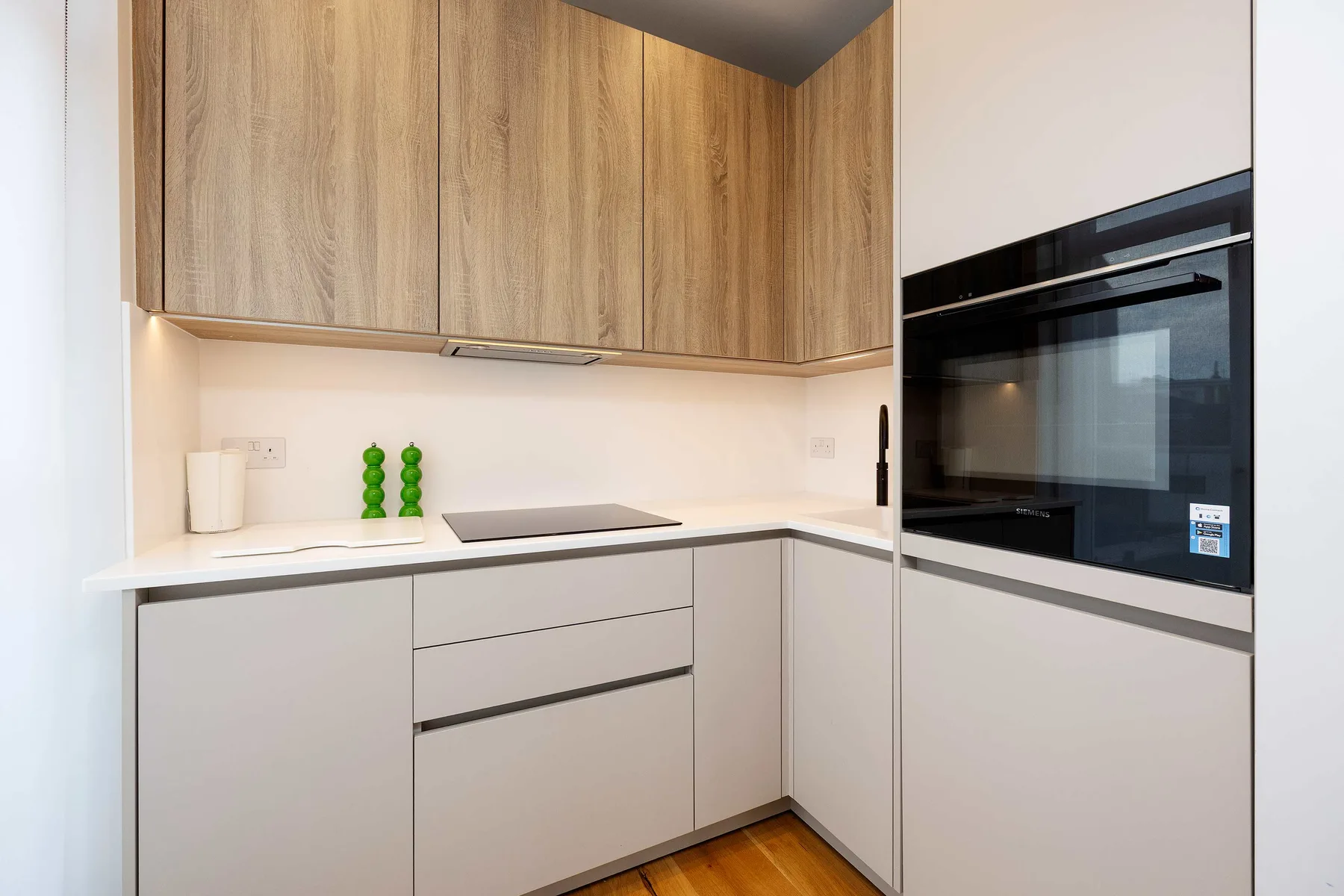Una cocina compacta con armarios de madera, una placa de cocción y un horno integrado.