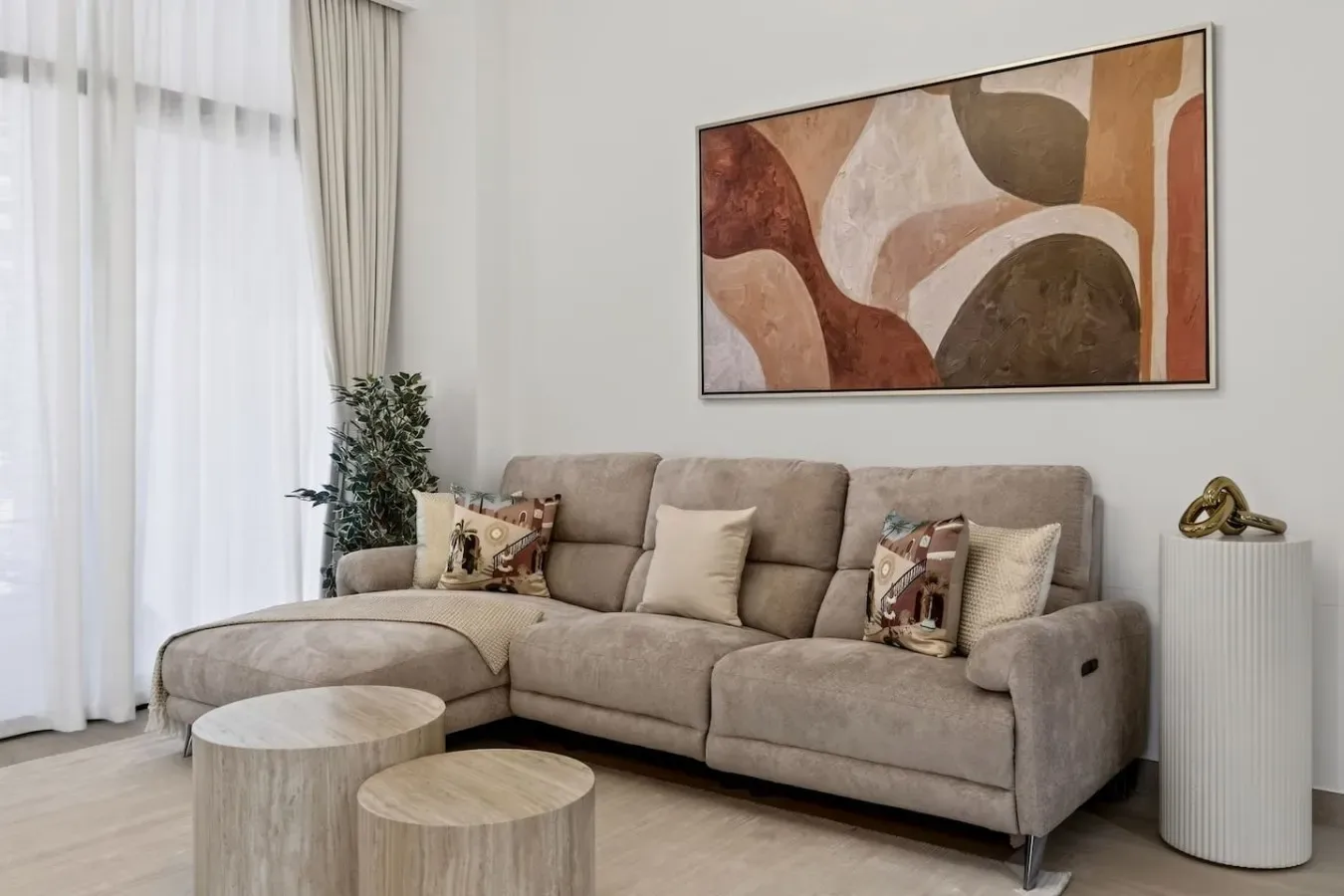 A living room with a sectional sofa, round coffee tables, and abstract wall art.