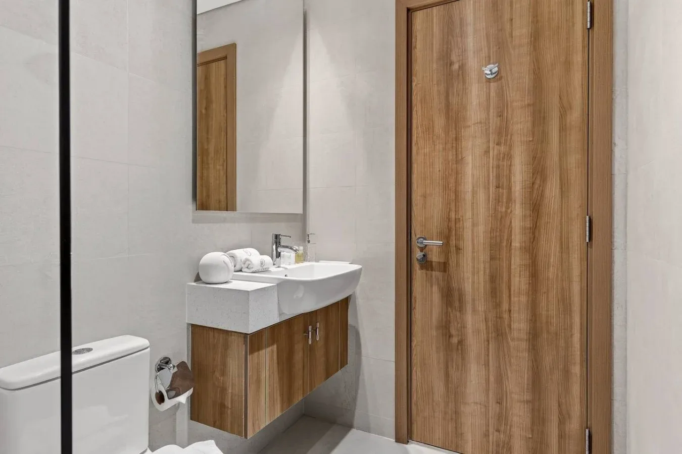 A bathroom with a sink, mirror, and wooden door.
