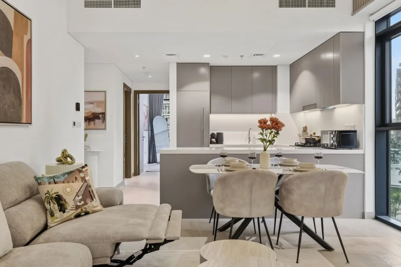 An open-plan living room and kitchen with a dining table and upholstered seating.