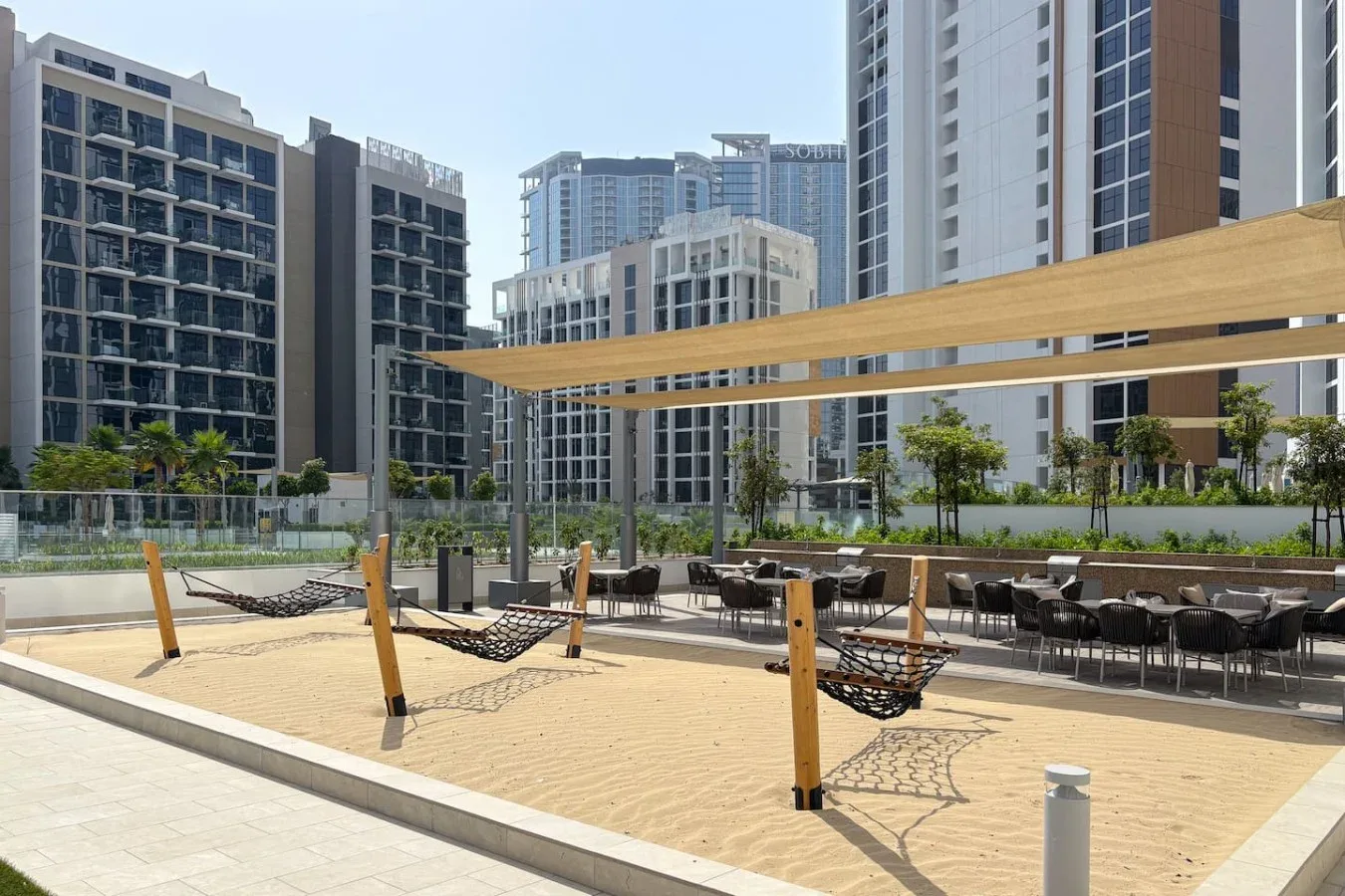 An outdoor courtyard with hammock seating beneath a wooden shade structure.
