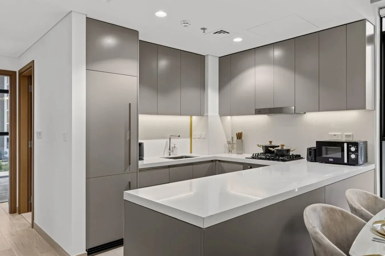 A modern kitchen with gray cabinets, a stainless steel refrigerator, and a white island.