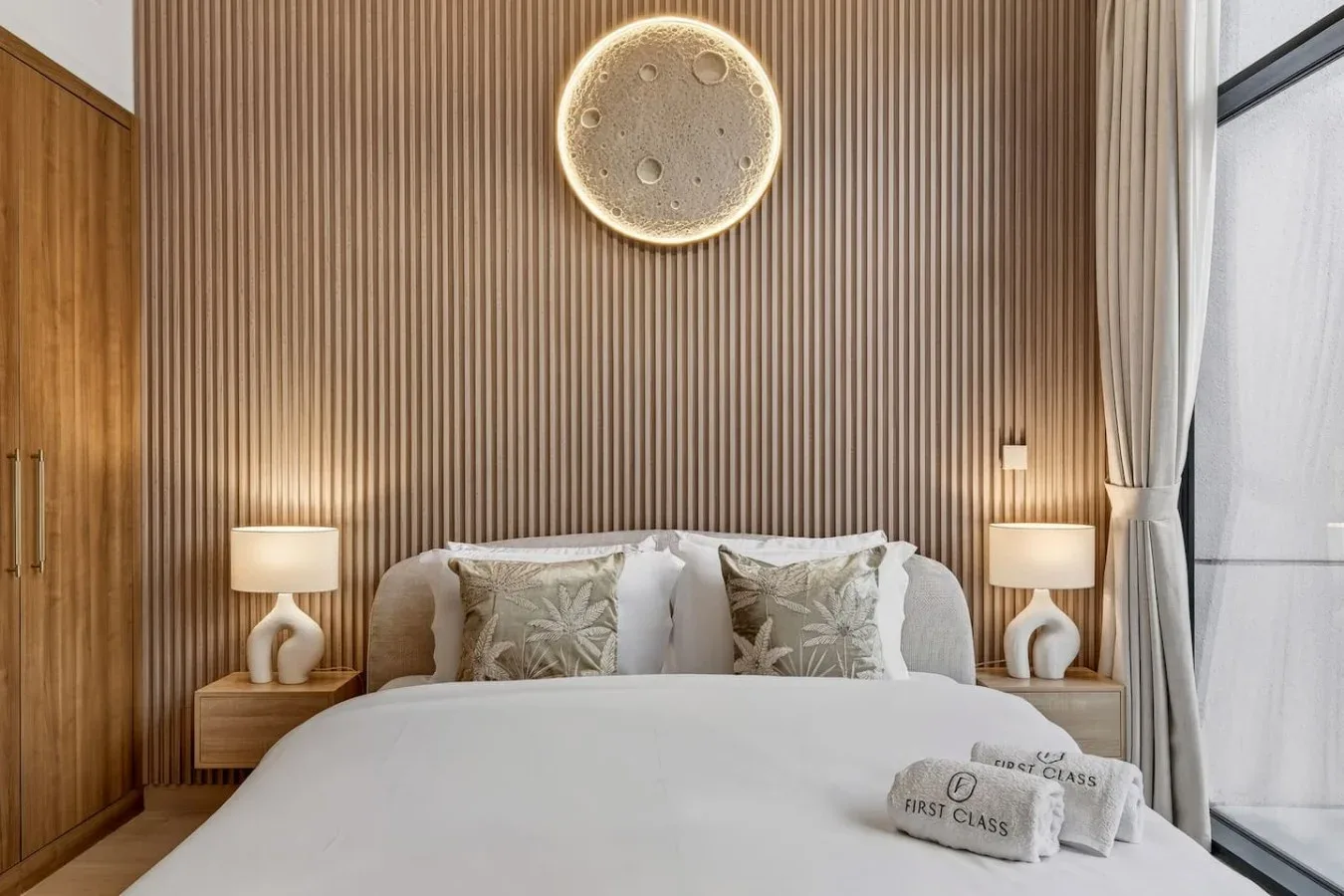 A bedroom with a neatly made bed and a ribbed accent wall.