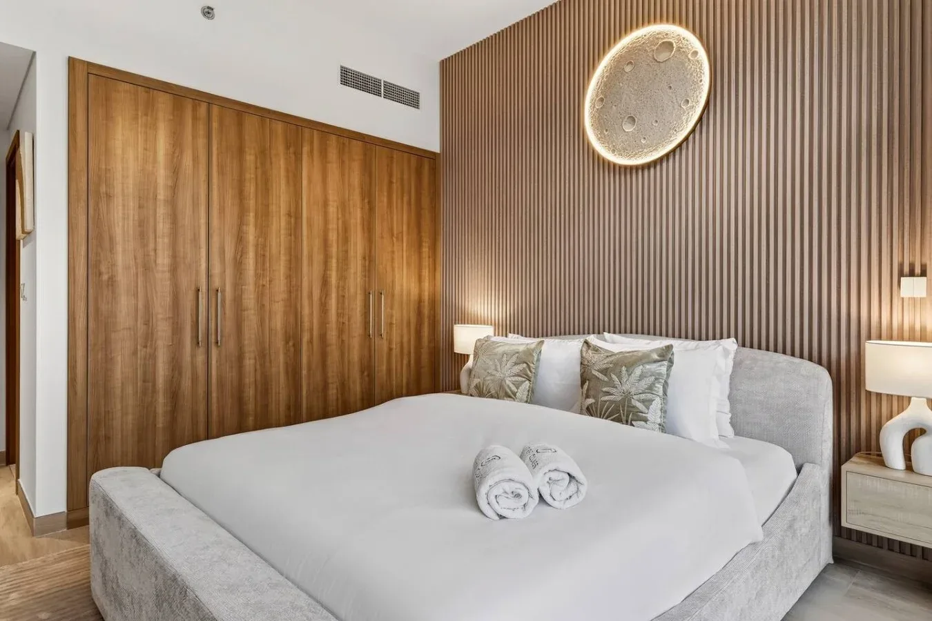 A bedroom with a neatly made bed and wooden wardrobe.