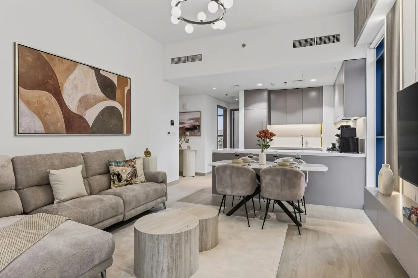 A modern living and dining area opens onto a kitchen with a breakfast counter.