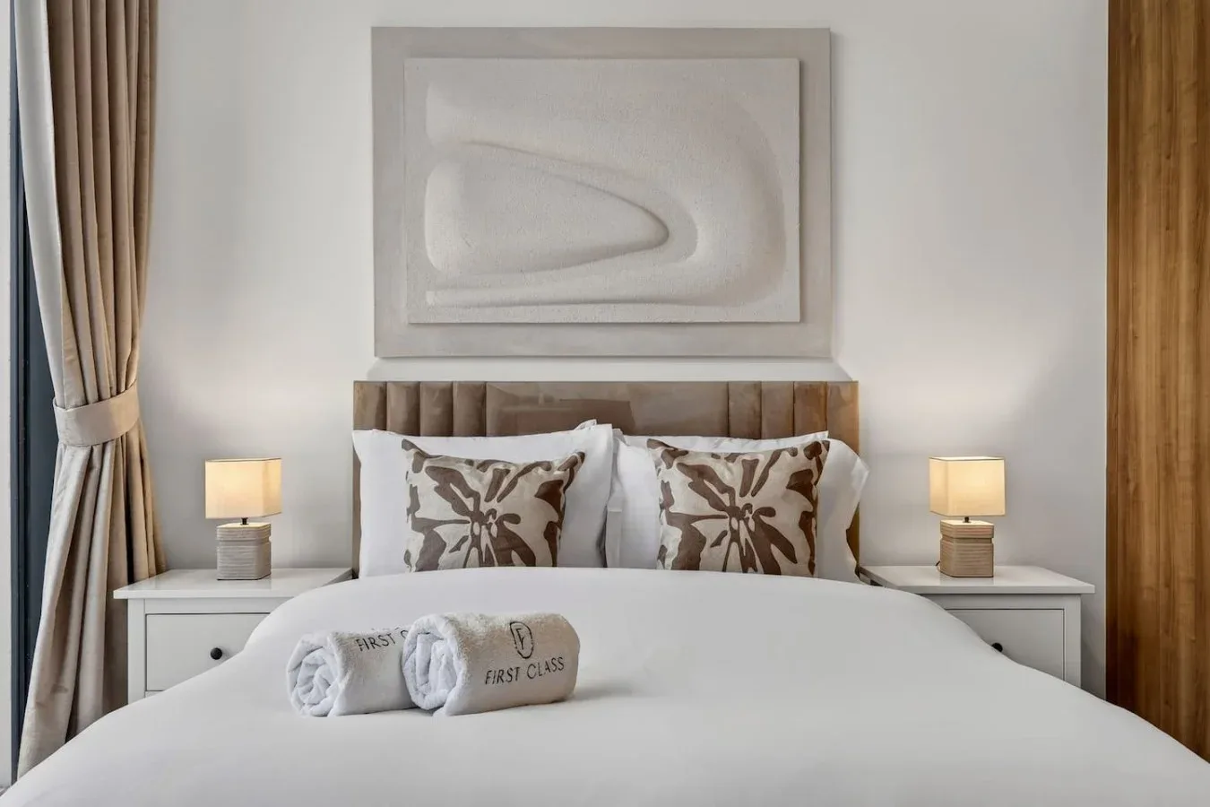 A neatly made bedroom with patterned pillows and matching bedside lamps.