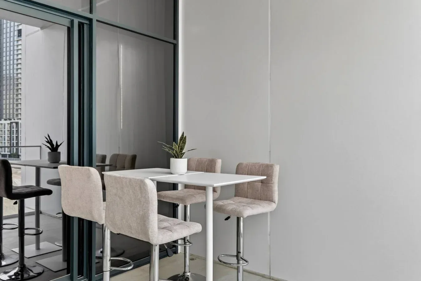 A dining area with a table, upholstered seating, and potted plants.