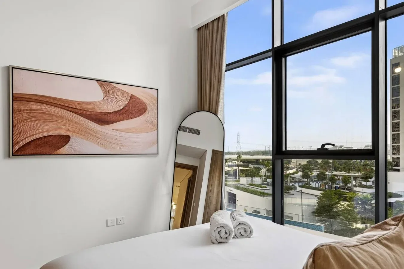 A bright bedroom with a large window overlooking the surrounding area.