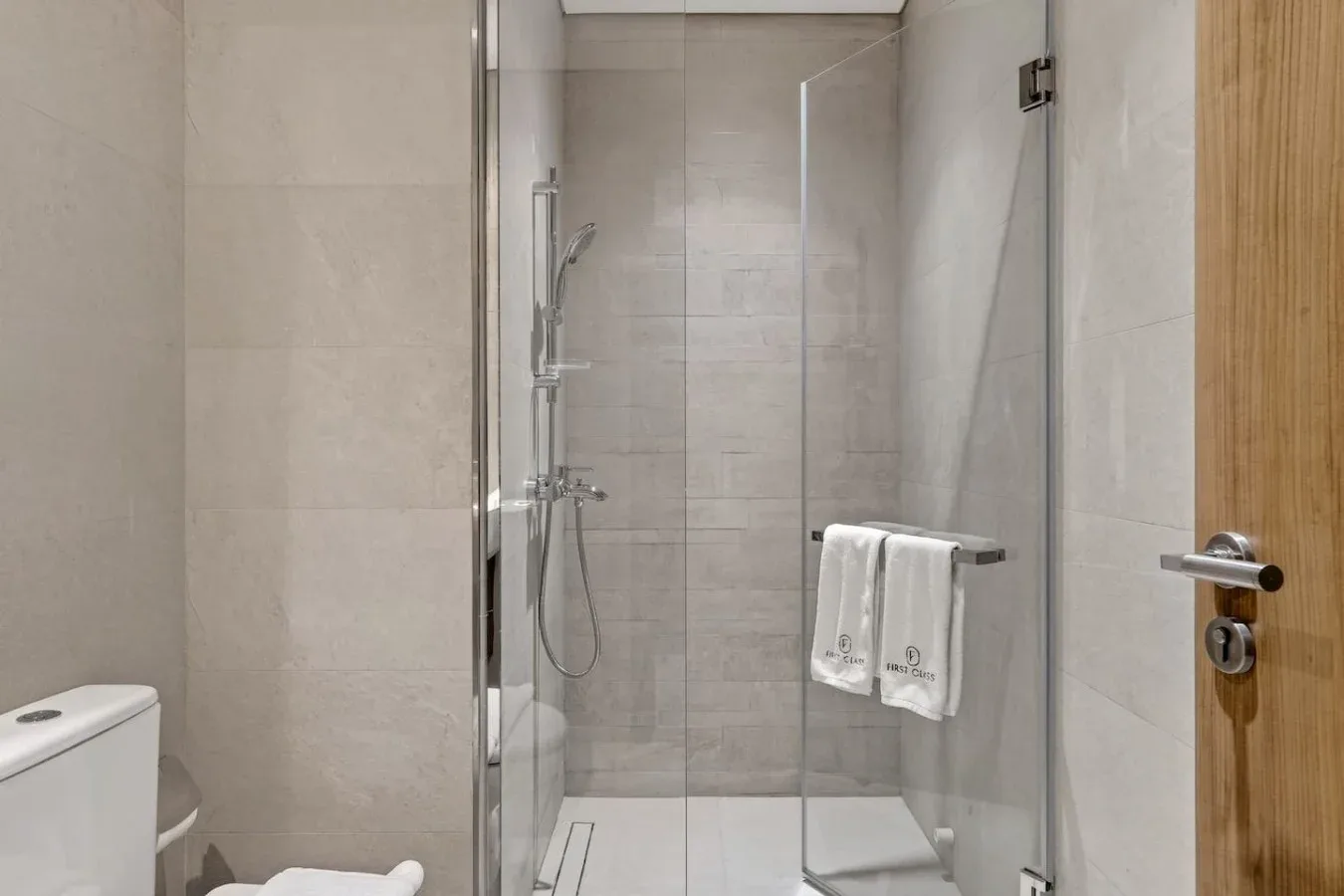 A tiled bathroom with a glass shower and towels hanging on a rail.