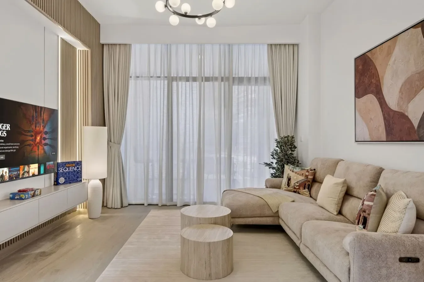 A bright living room has floor-to-ceiling curtains and a large sectional sofa.