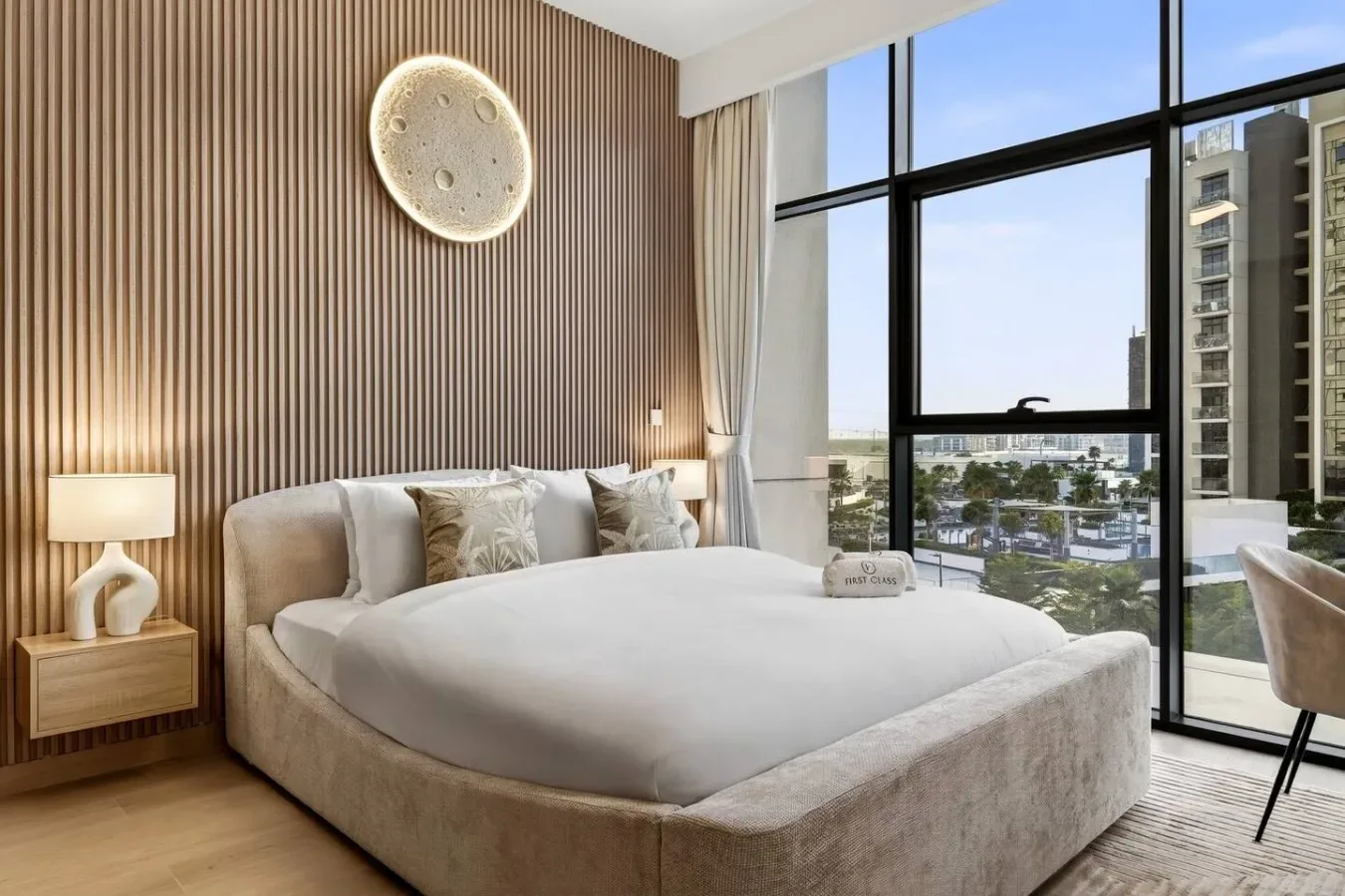 A bedroom with a large bed beside floor-to-ceiling windows.