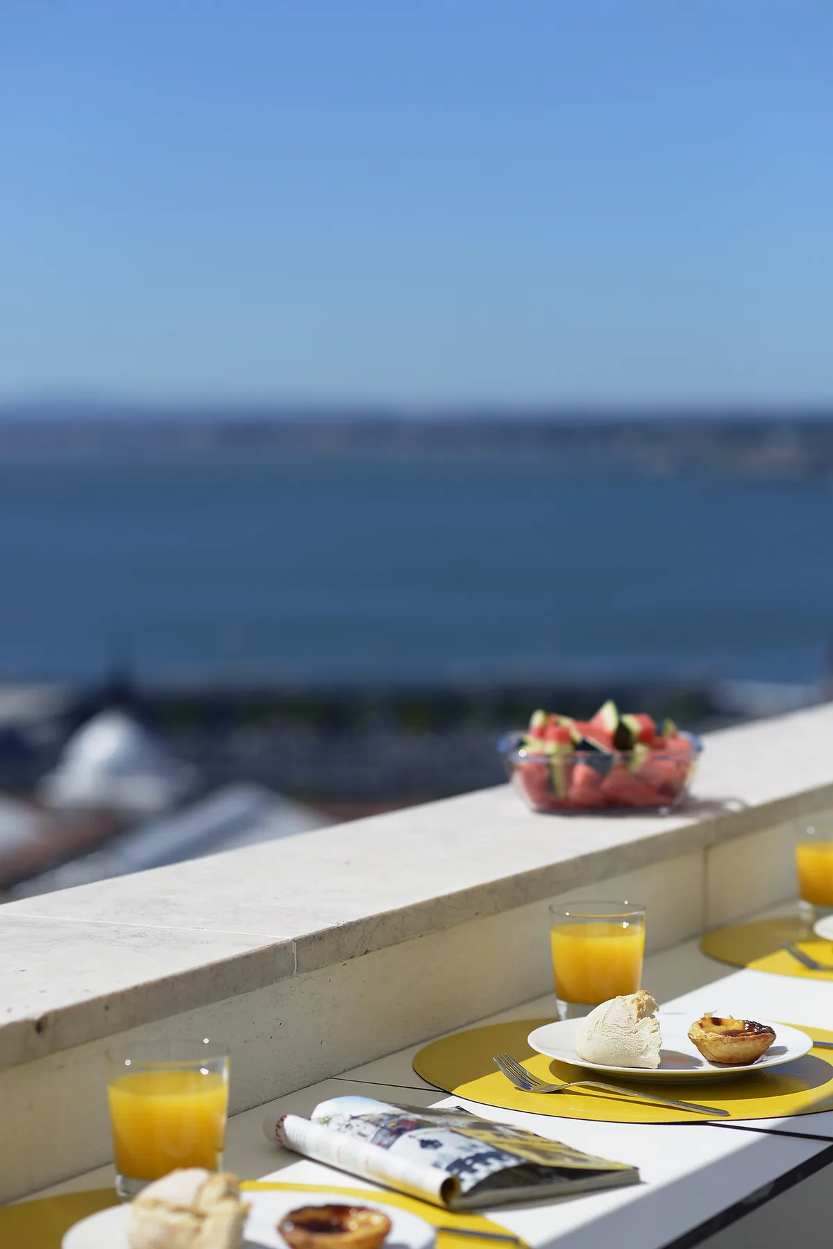 A breakfast spread sits on a terrace ledge overlooking the water.