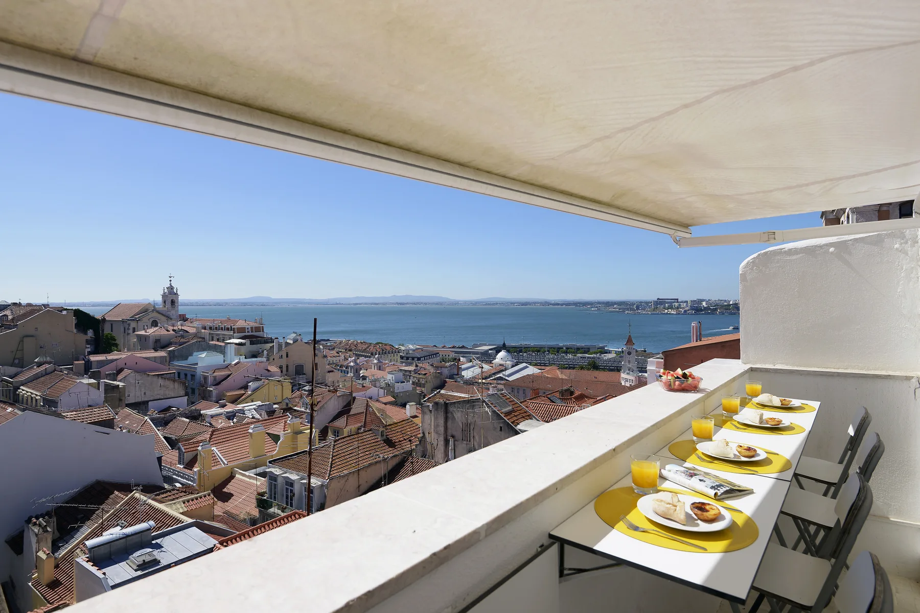 A rooftop terrace overlooks red-tiled buildings and the water.