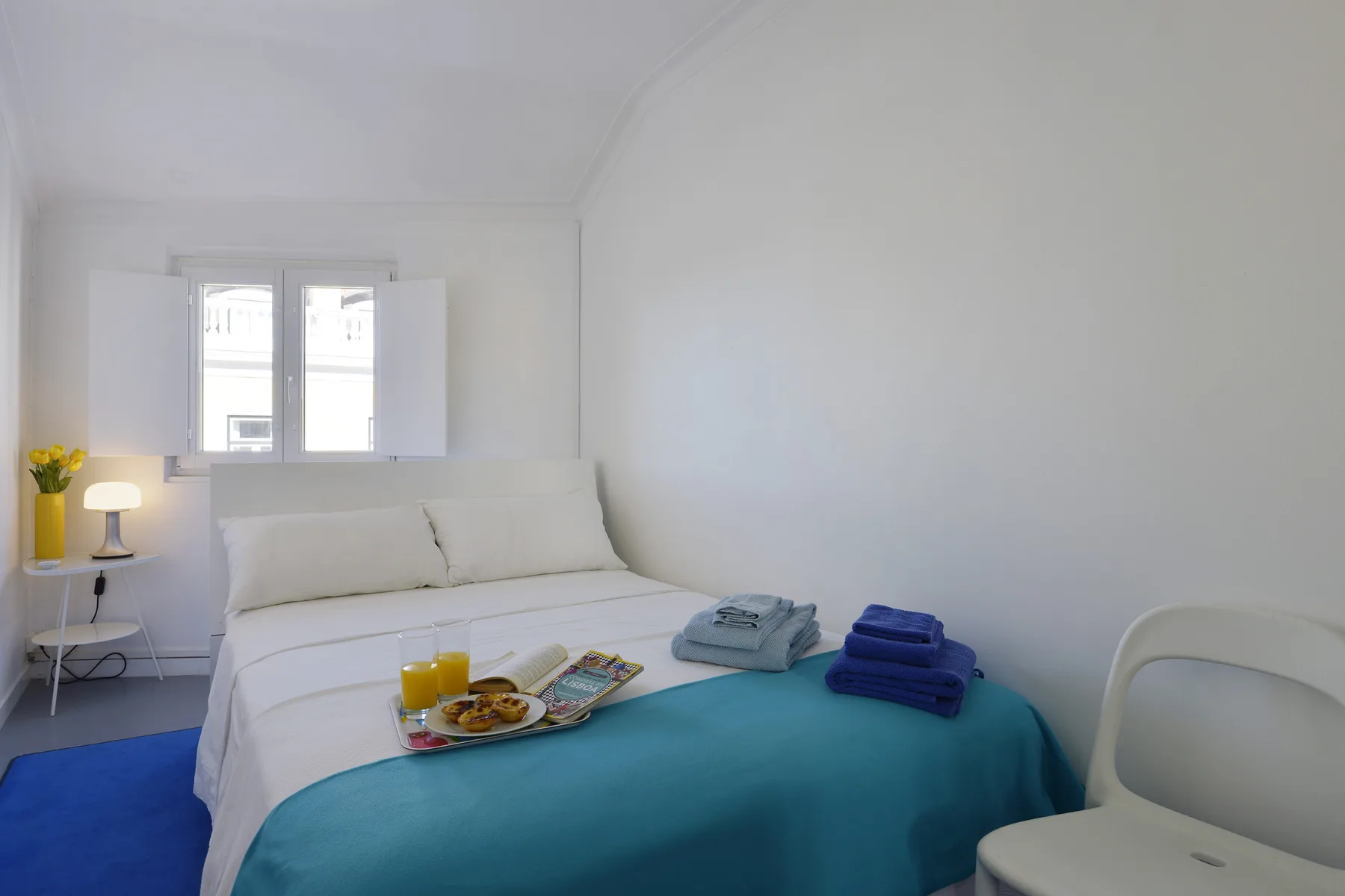 A bright bedroom with a neatly made bed and a small window.