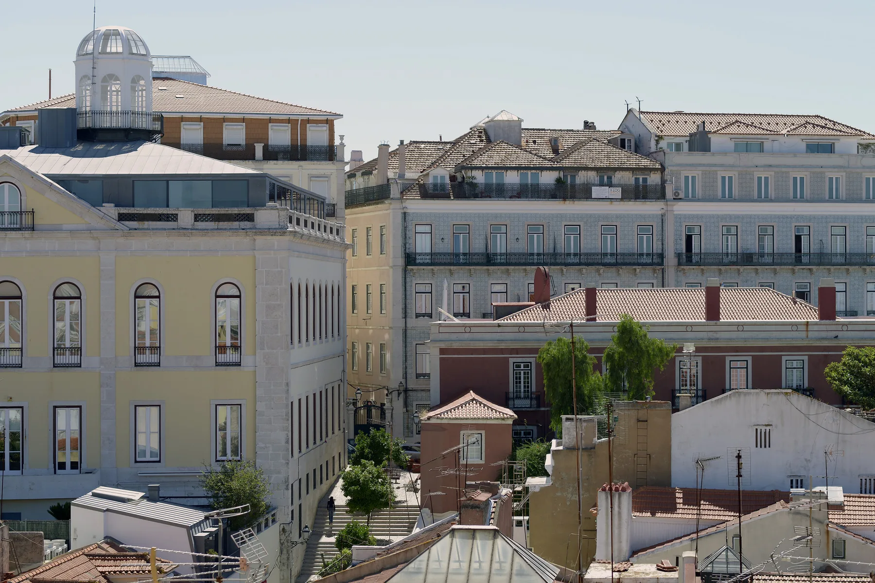 A cityscape of Lisbon rooftops and historic buildings under a clear sky.