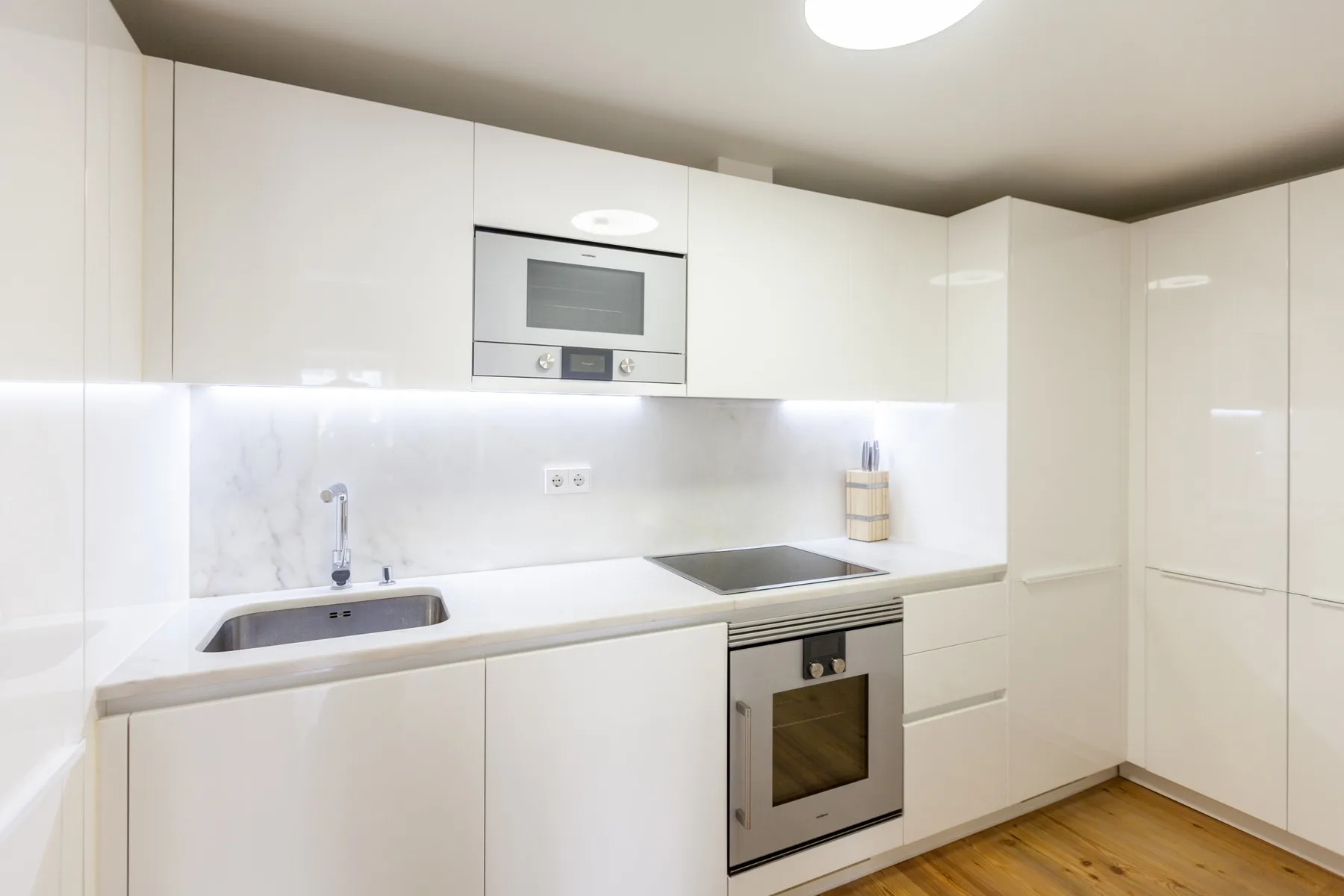 Una cocina moderna con gabinetes blancos, encimera y electrodomésticos integrados.