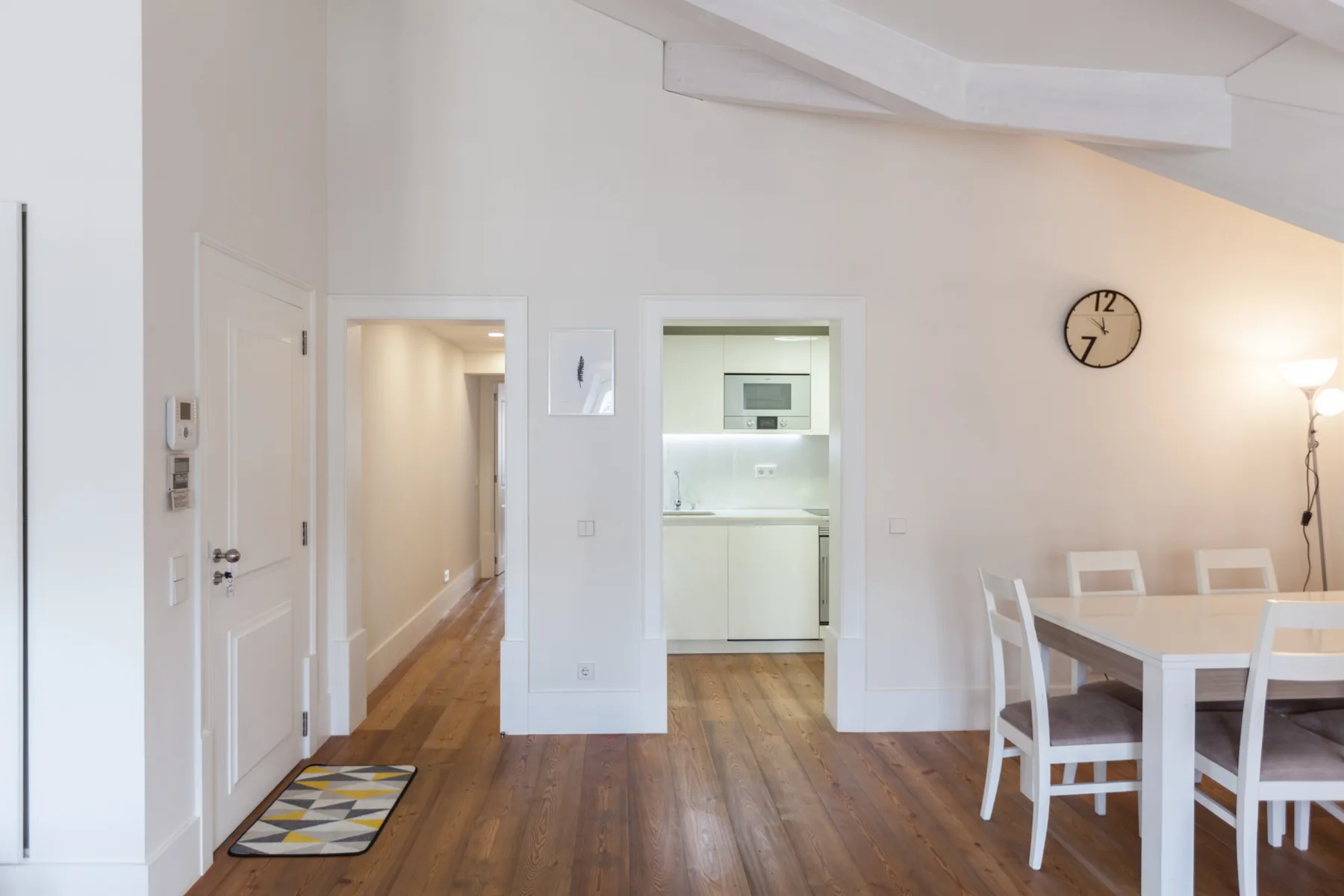 Un comedor luminoso con una mesa blanca junto a una puerta abierta a la cocina.