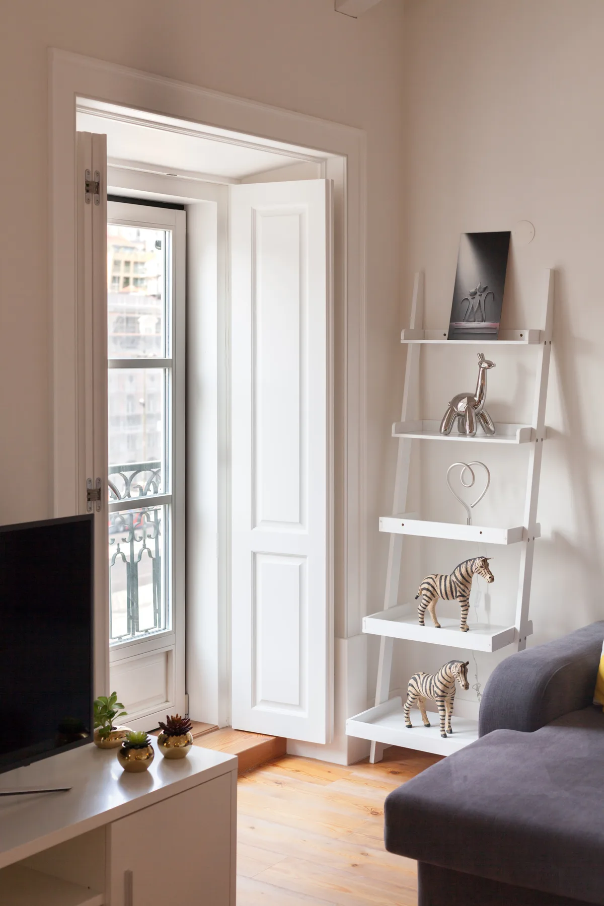 Sala de estar con televisor, asientos y una ventana alta.