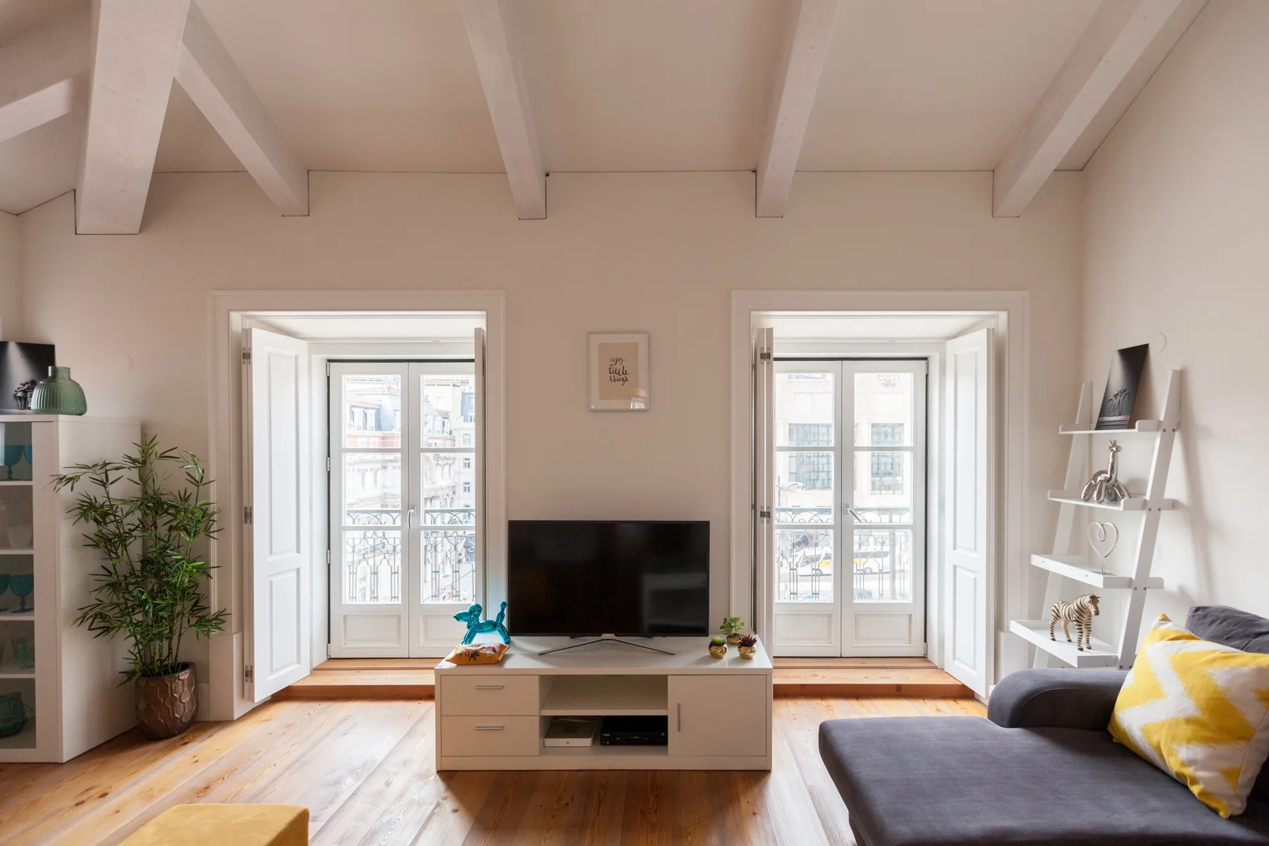 Una sala luminosa con asientos, un televisor y ventanas altas.