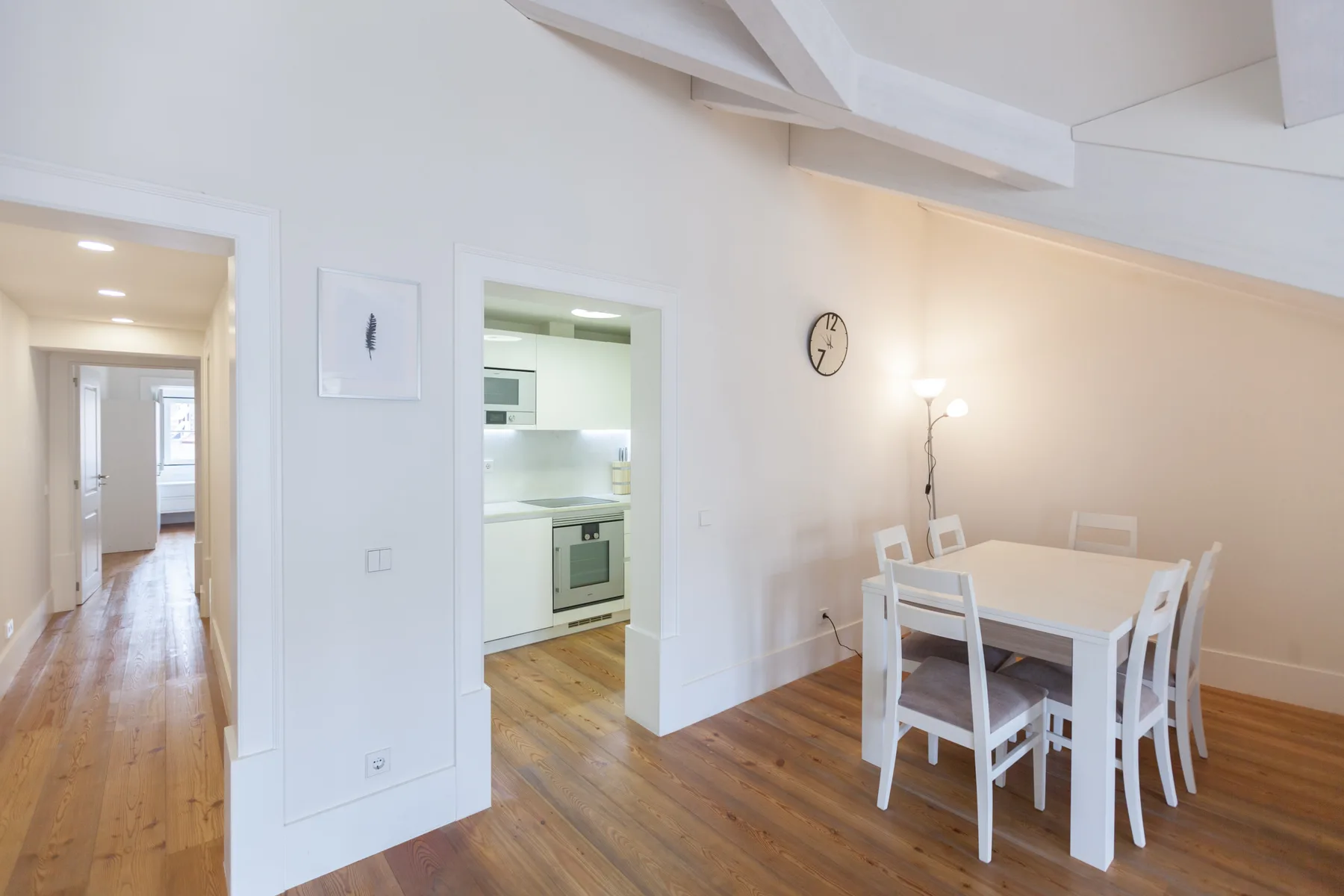Un comedor luminoso con una mesa blanca junto a una cocina abierta.