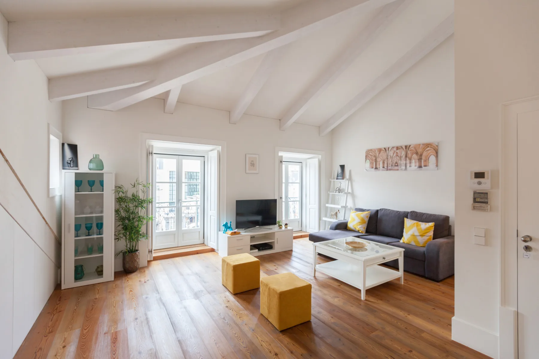 Una sala de estar luminosa con asientos y una mesa de centro bajo un techo inclinado.