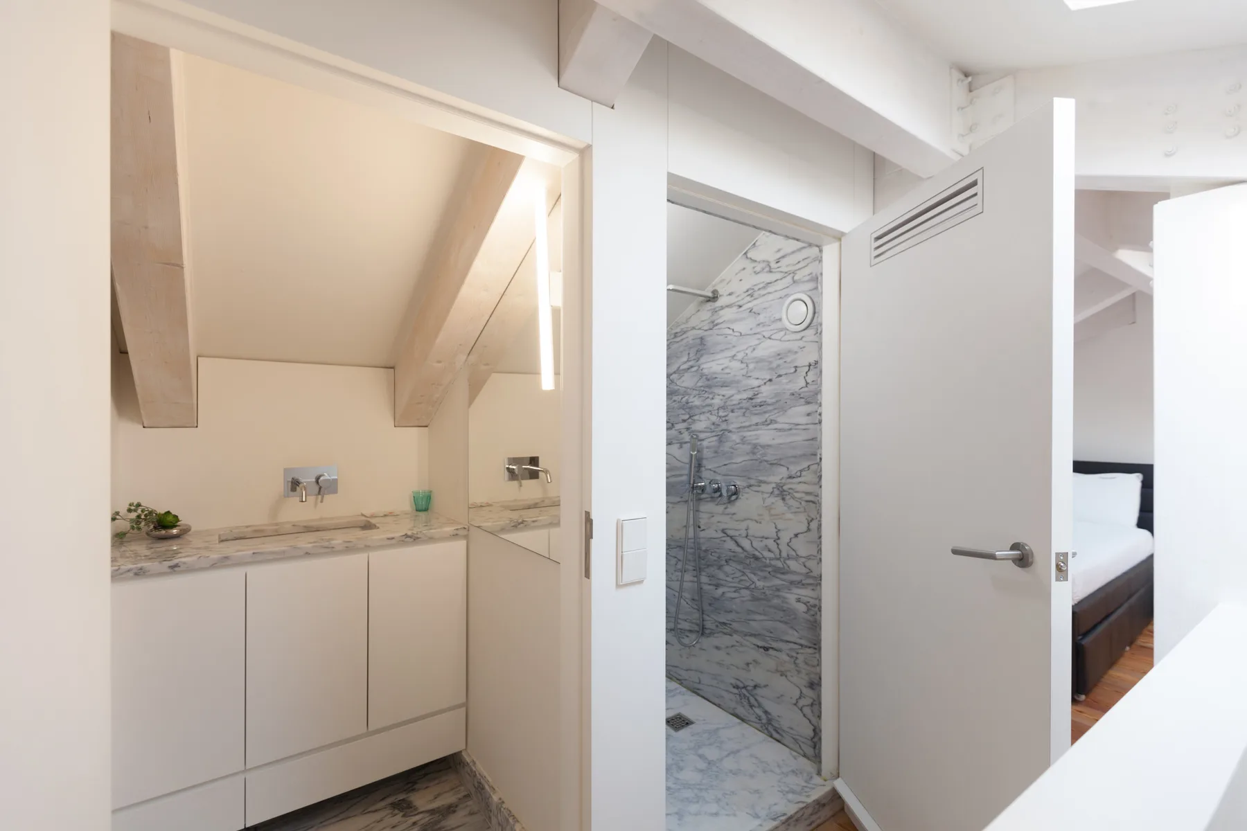 Un pasillo luminoso da a un baño y a una pequeña zona de cocina.