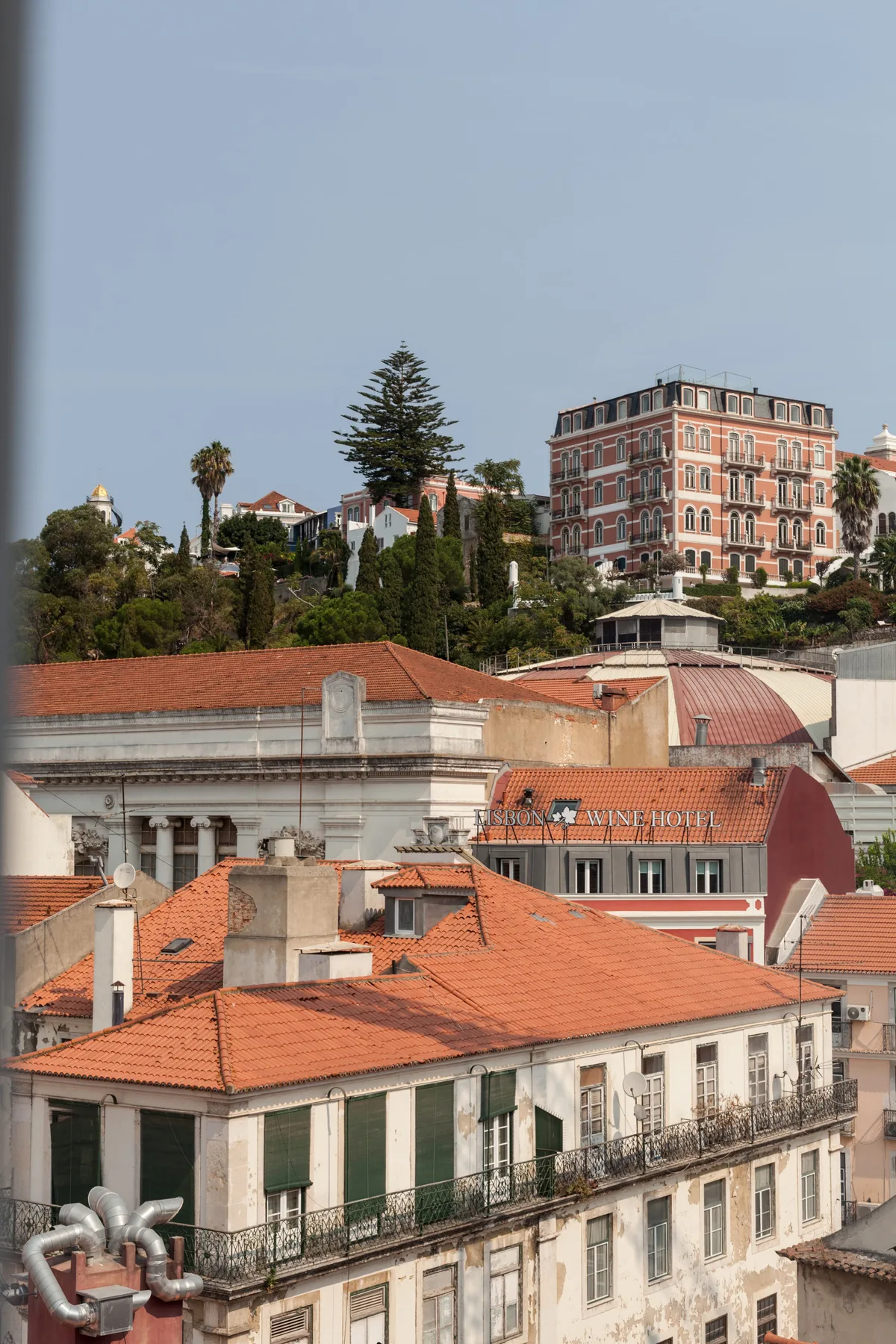 Vista urbana de edificios próximos con tejados de teja roja y un edificio más alto en la ladera.
