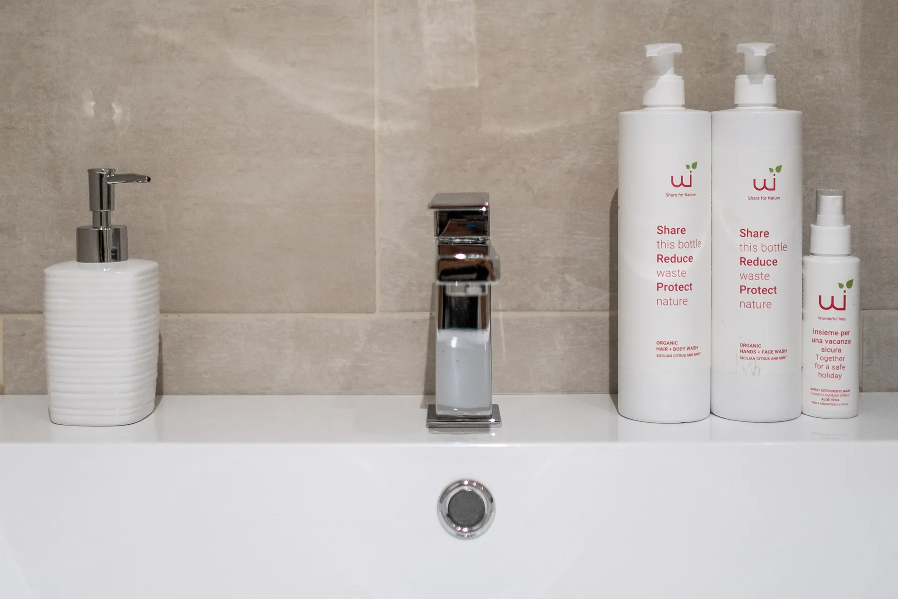 Lavabo de baño con grifo cromado y productos de aseo sobre el borde.