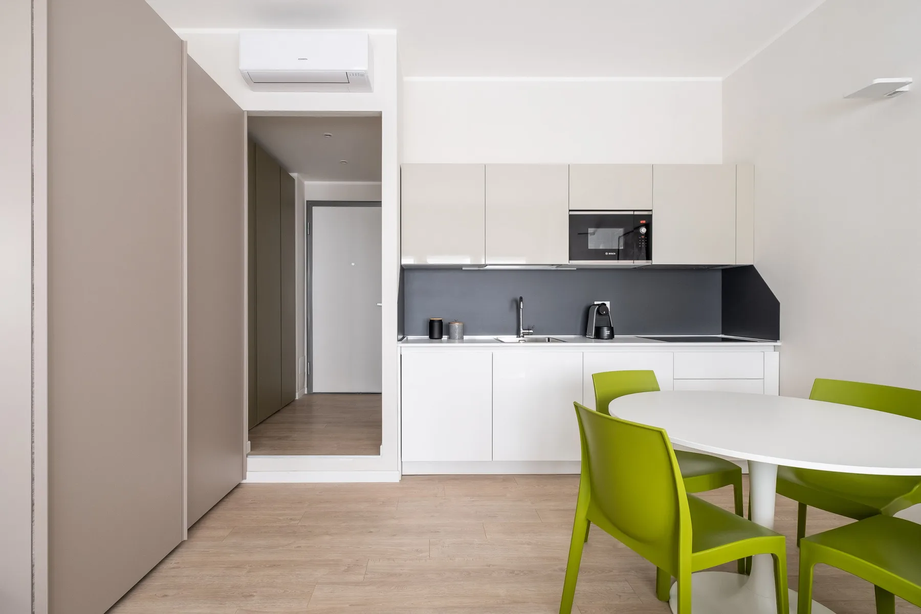 Cocina y comedor modernos con armarios blancos y asientos de color verde brillante.