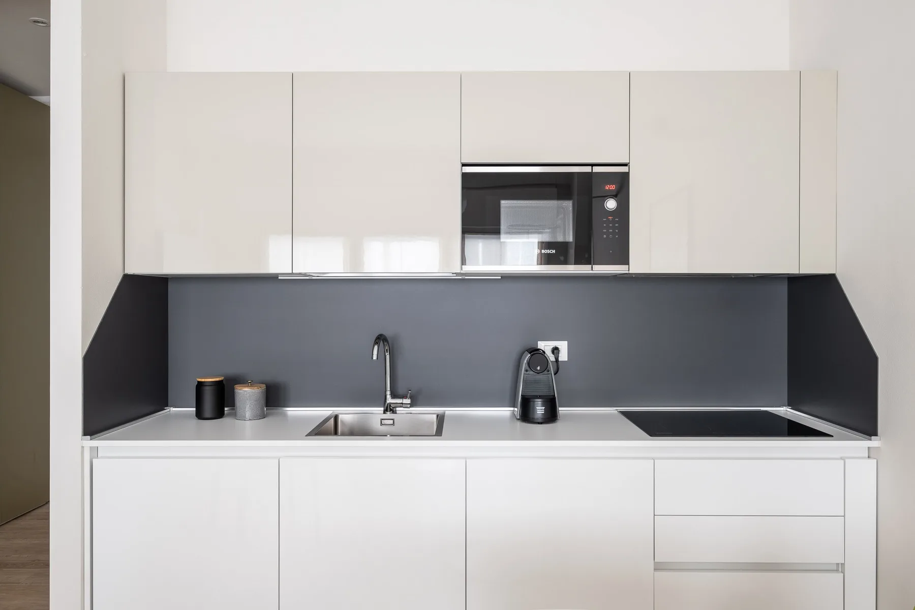 Una cocina moderna con gabinetes blancos, un salpicadero oscuro y un microondas integrado.