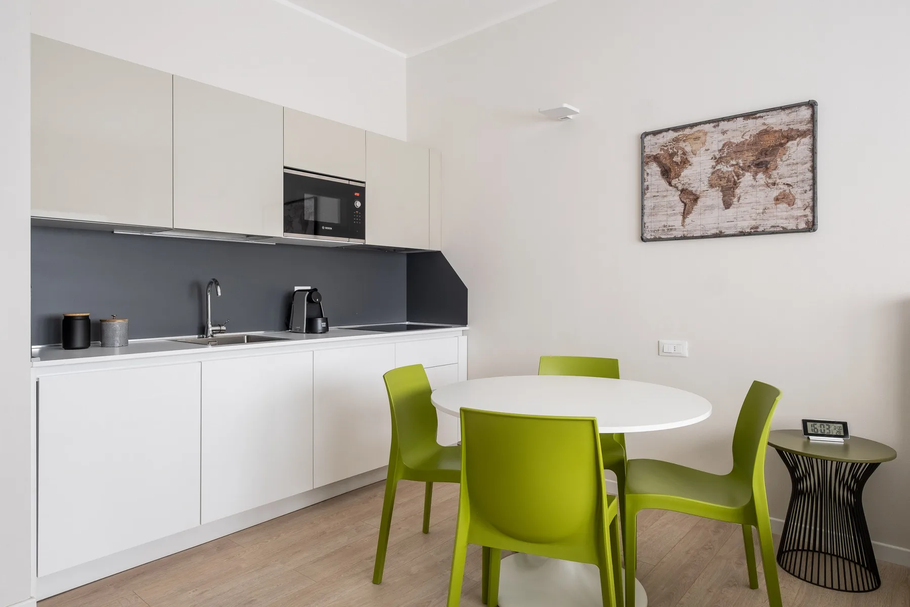 Una cocina compacta y comedor con gabinetes blancos y asientos verdes.