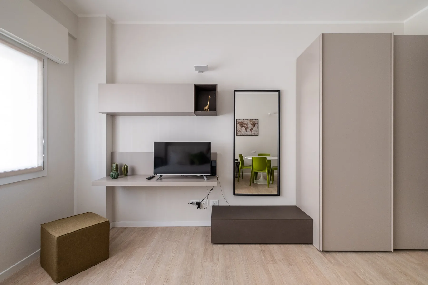 Una sala luminosa con televisor, almacenamiento bajo y una ventana grande.