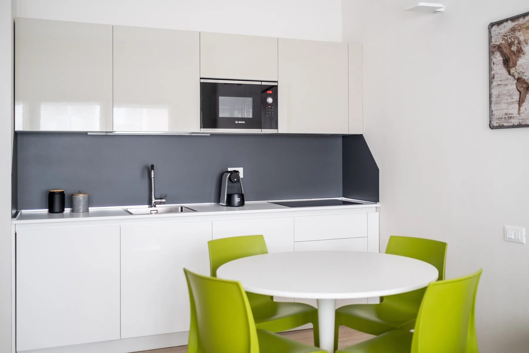 Una cocina moderna con armarios blancos, un salpicadero oscuro y una mesa redonda.