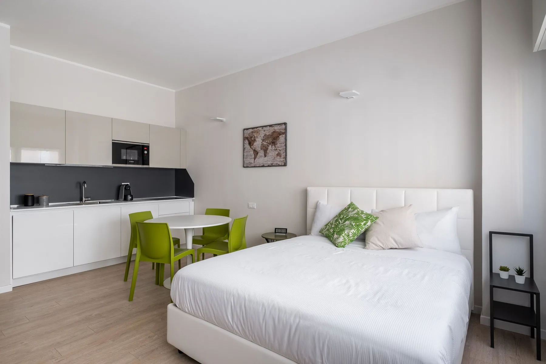 Un dormitorio luminoso con una cama grande y una pequeña zona de cocina.