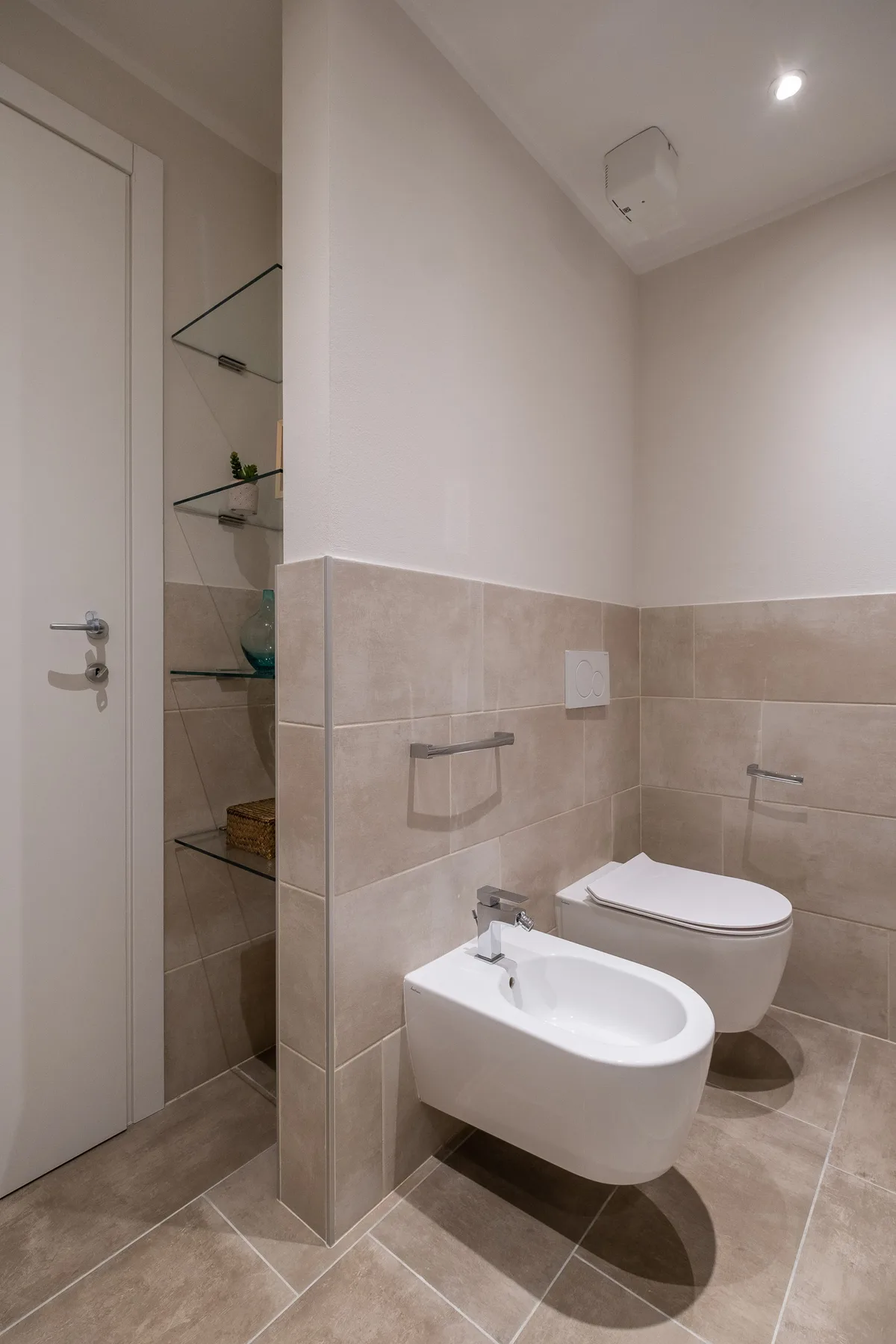 Un baño con azulejos, lavabo suspendido e inodoro.