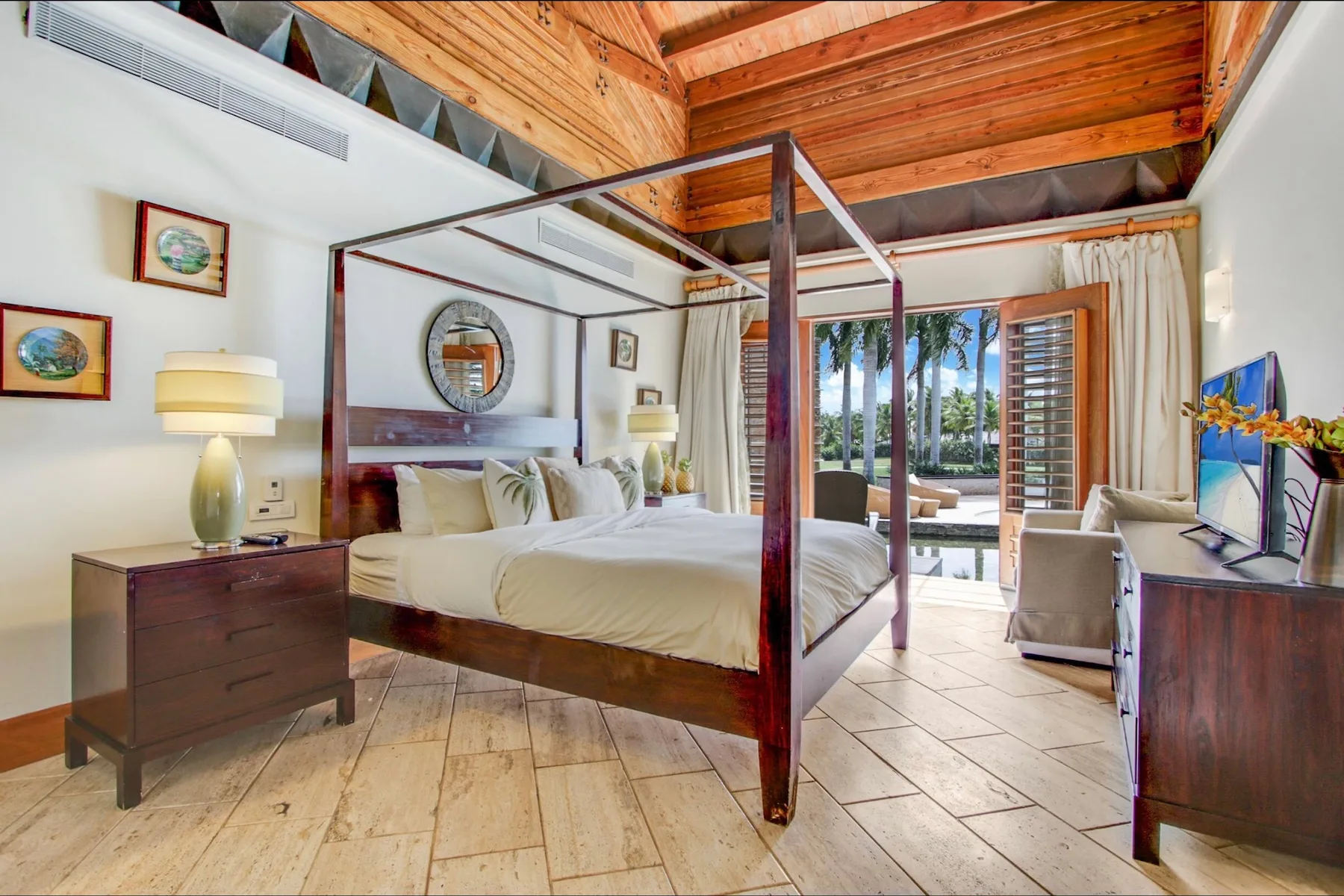 A bedroom with a four-poster bed and glass doors opening onto a patio.