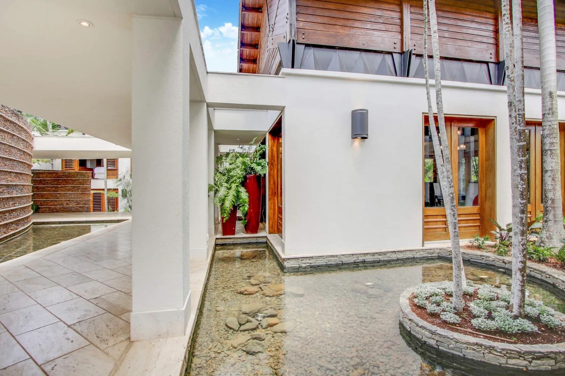 A modern courtyard with a shallow water feature and wooden upper facade.