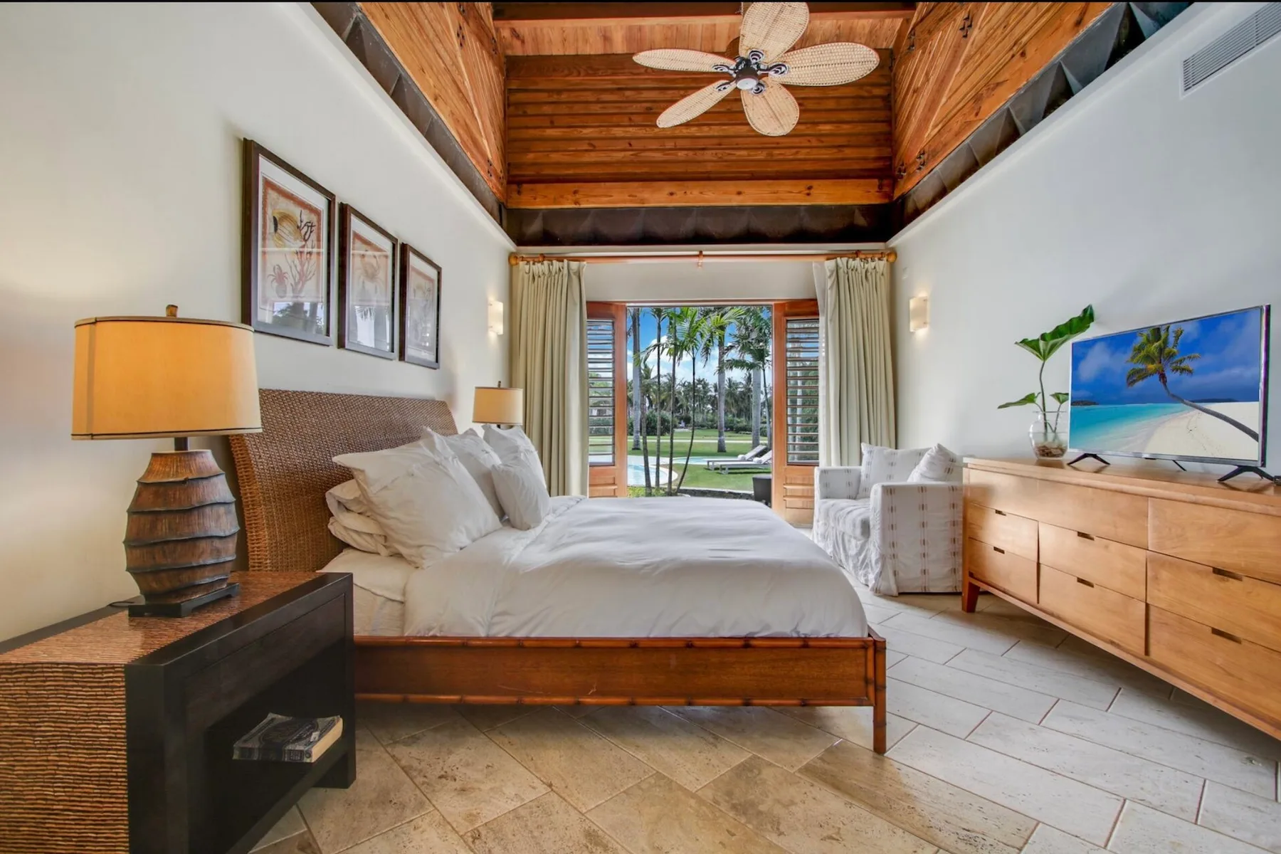 A bedroom with a wooden bed, bedside lamps, and a view through open doors.