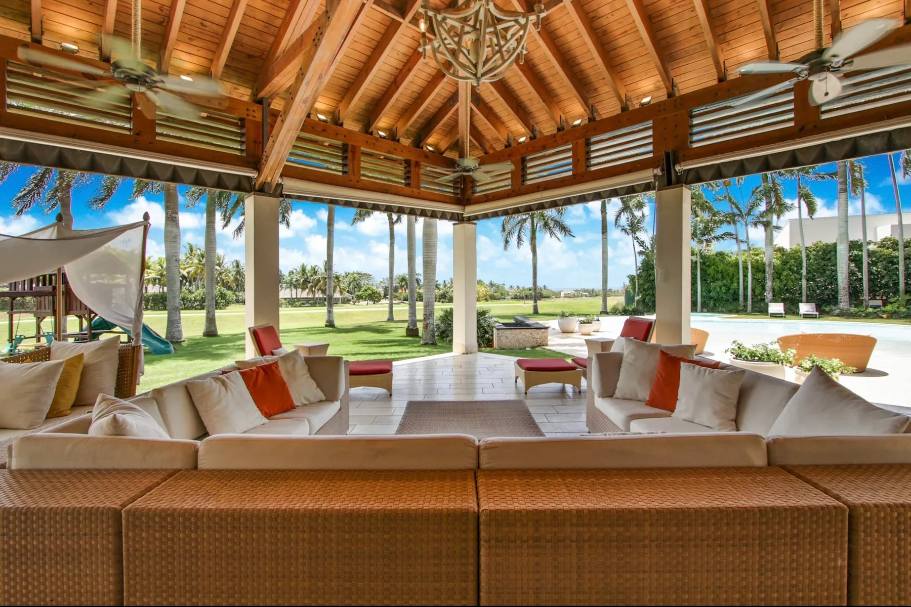 An open-air lounge with cushioned seating overlooks a landscaped lawn.