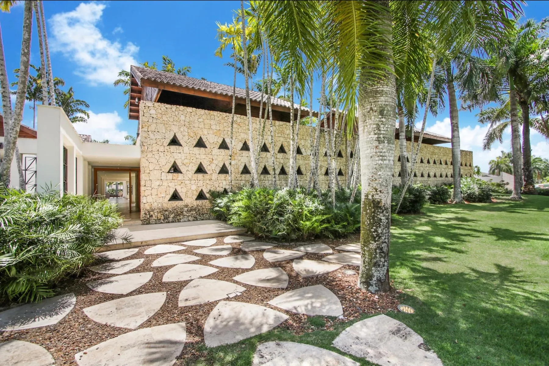 A landscaped garden and stone walkway lead toward a building with patterned walls.