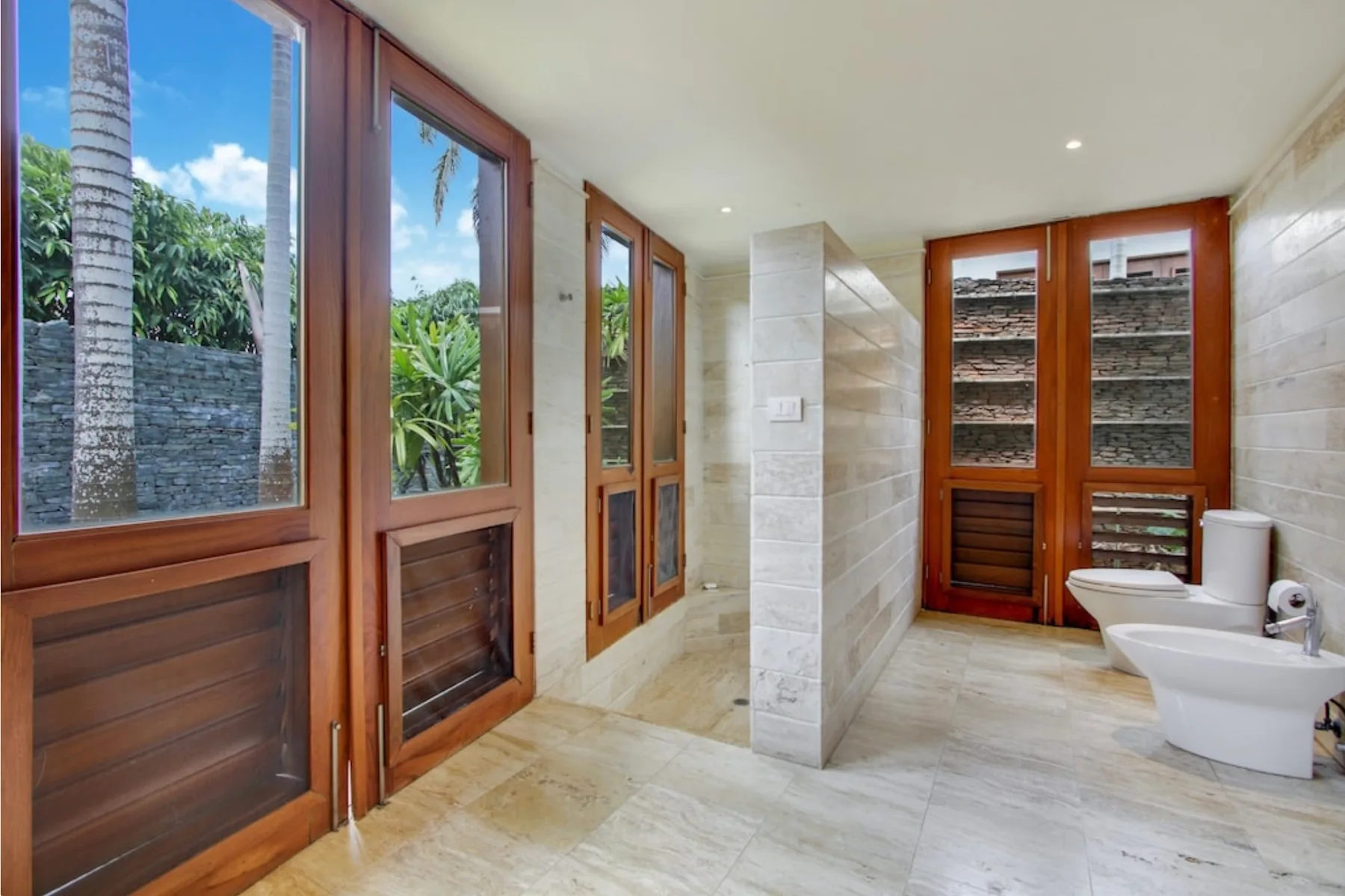 A bright bathroom with wooden-framed windows and bathroom fixtures.